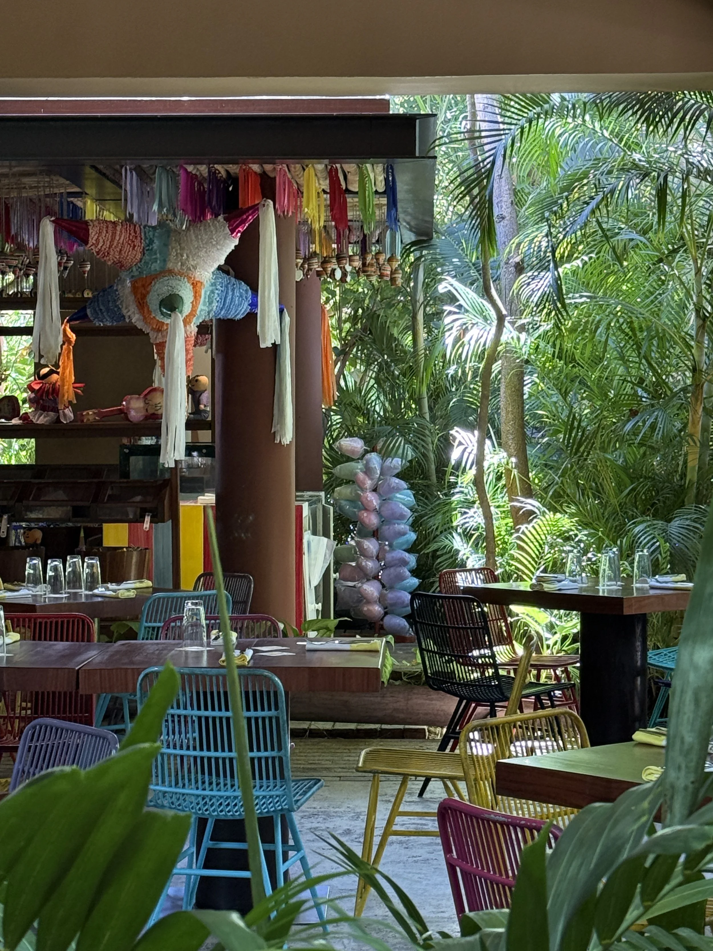 Open-air restaurant with colorful decor and jungle surroundings at Hotel Xcaret Mexico in Riviera Maya