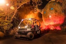 Amphibious jungle vehicle driving at night during Xplor Fuego adventure park, surrounded by fire-lit scenery.