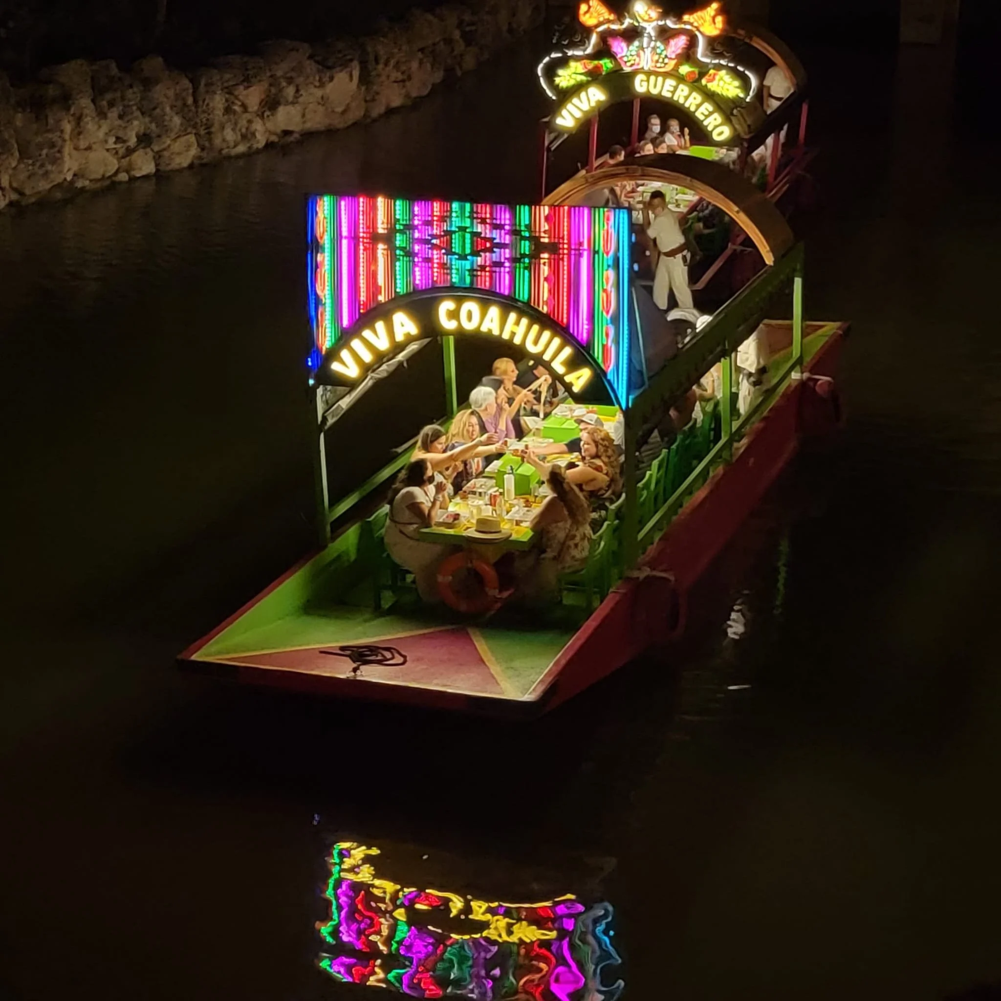 Xoximilco Cancun nighttime boat party with food, music, and guests celebrating on a trajinera.