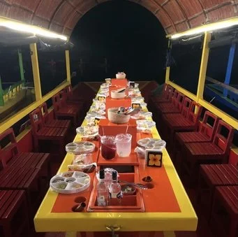 Traditional Mexican dinner setup on a trajinera during the Xoximilco Xcaret nighttime experience.