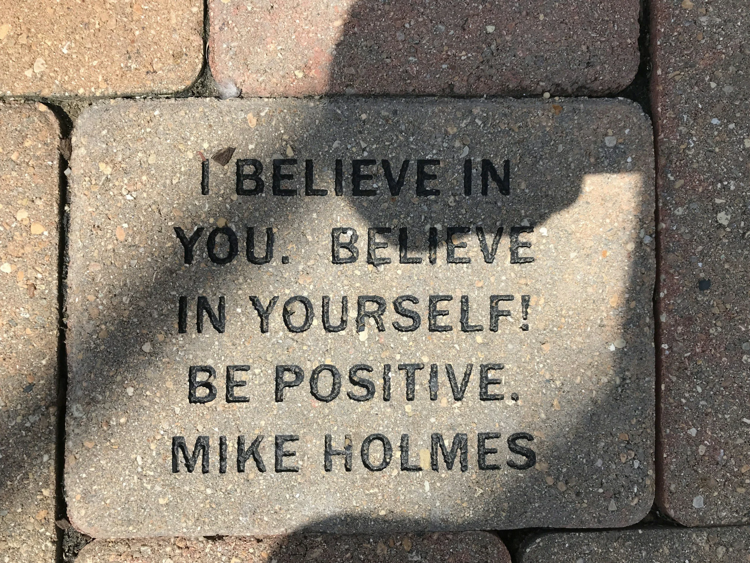 A brick sidewalk with words engraved in one brick that says, "I BELIEVE IN YOU. BELIEVE IN YOURSELF!"