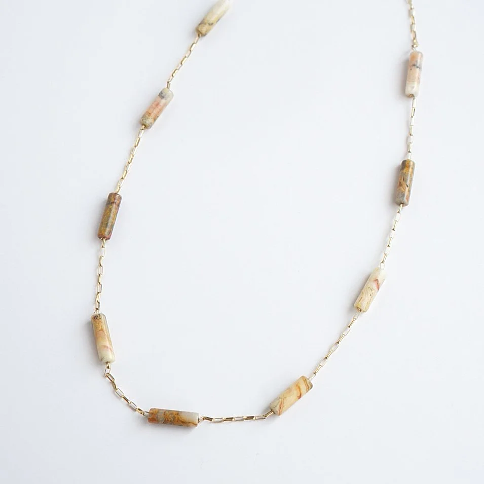 16 inch crazy lace agate tube bead necklace on 14k gold filled rolo chain laid flat on a white background