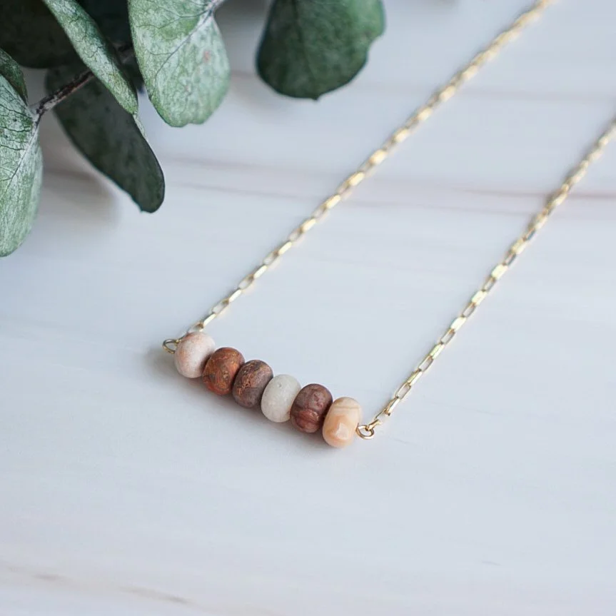 16 inch red lace agate bead bar necklace with matte gemstone beads on a 14k gold filled elongated rolo chain, styled with eucalyptus on white marble