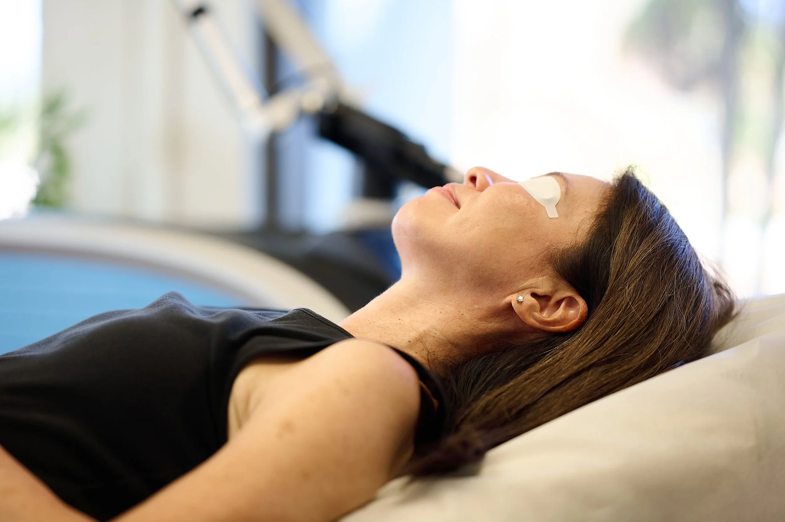 Woman lying in a hospital bed with an oxygen tube on her nose and a bandage on her forehead, appearing to be resting or unconscious.