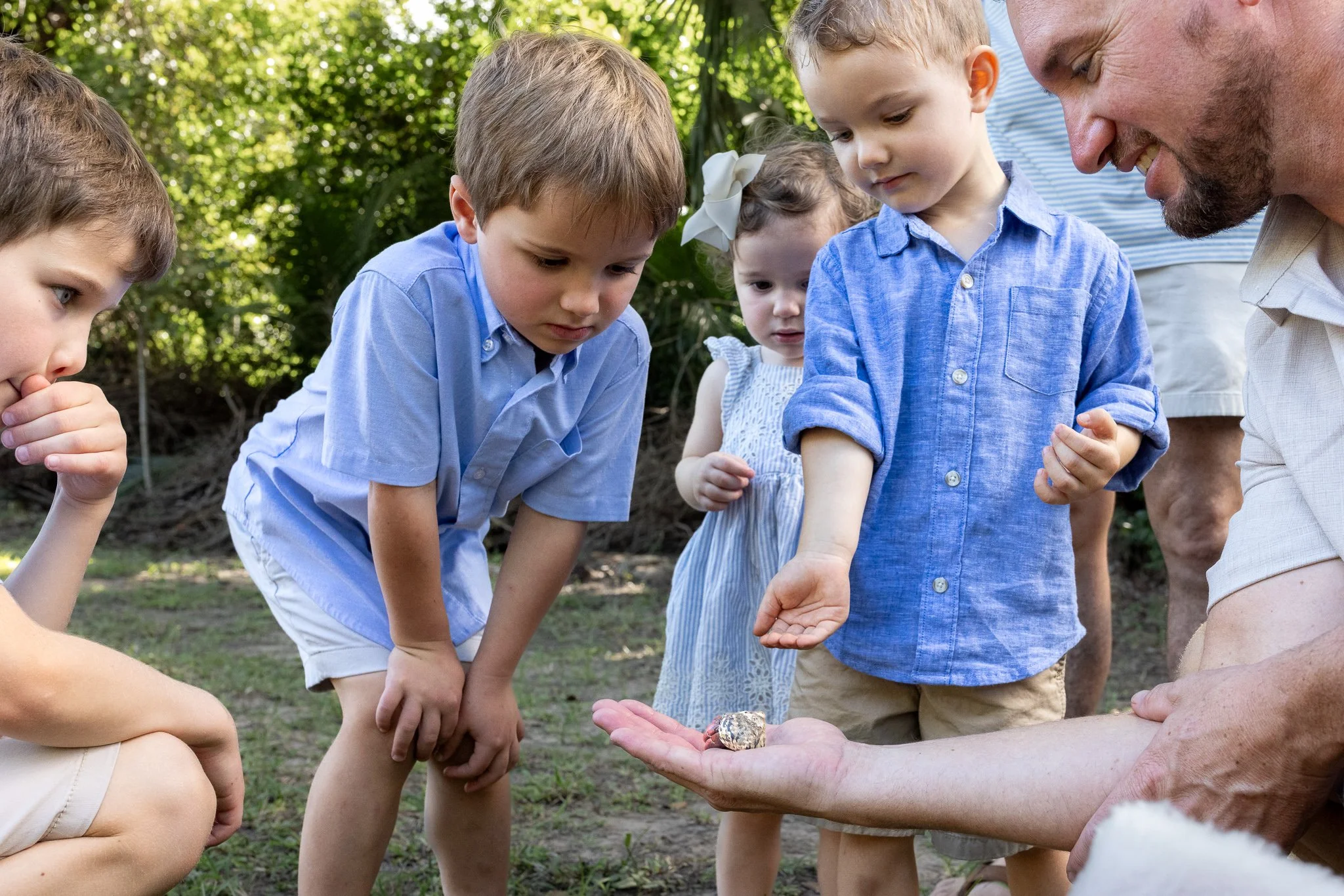 A man dressed as Santa Claus showing a ring to children outdoors on a sunny day.