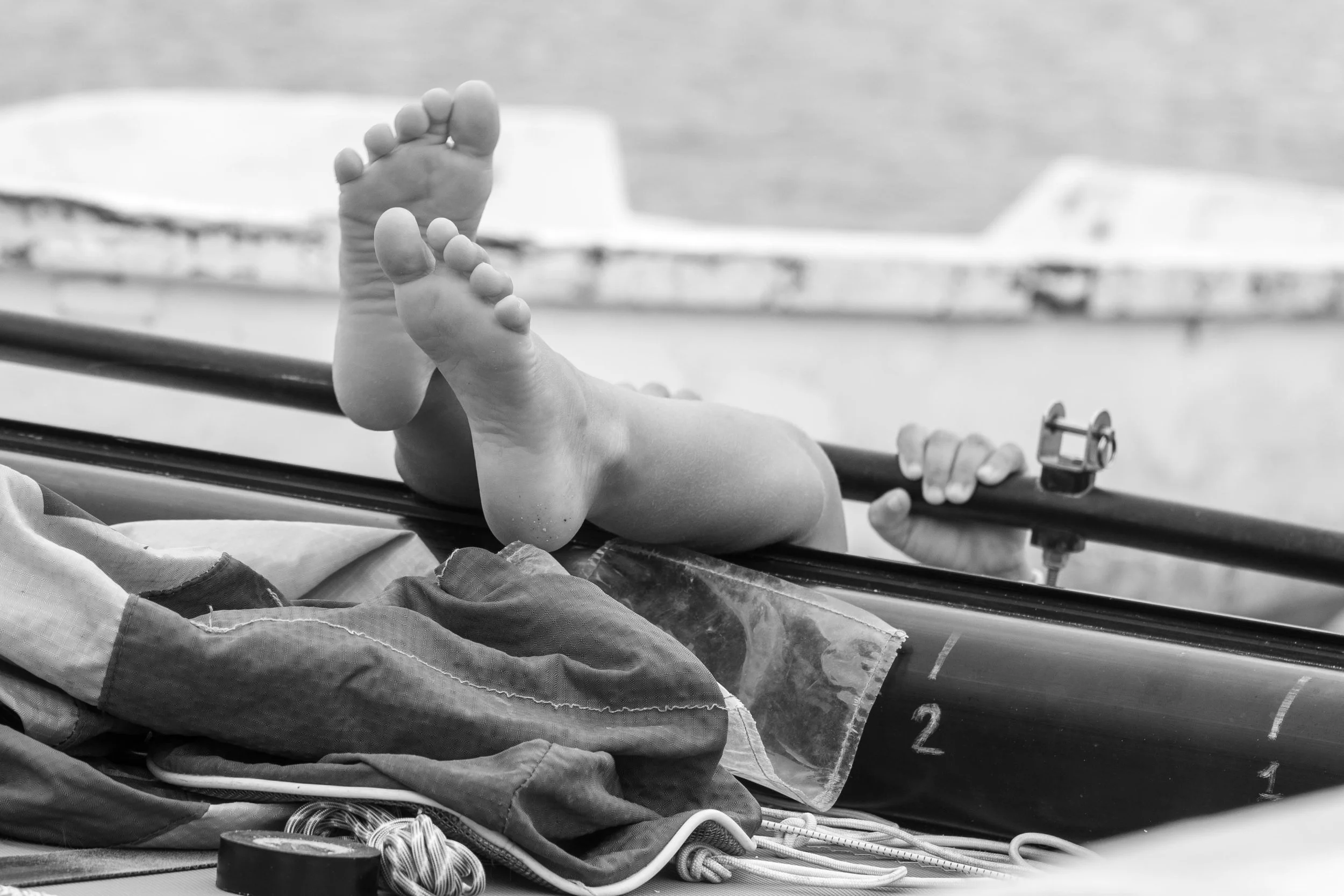Baby lying in a medical bassinet, legs raised, feet visible, in a black and white photo.