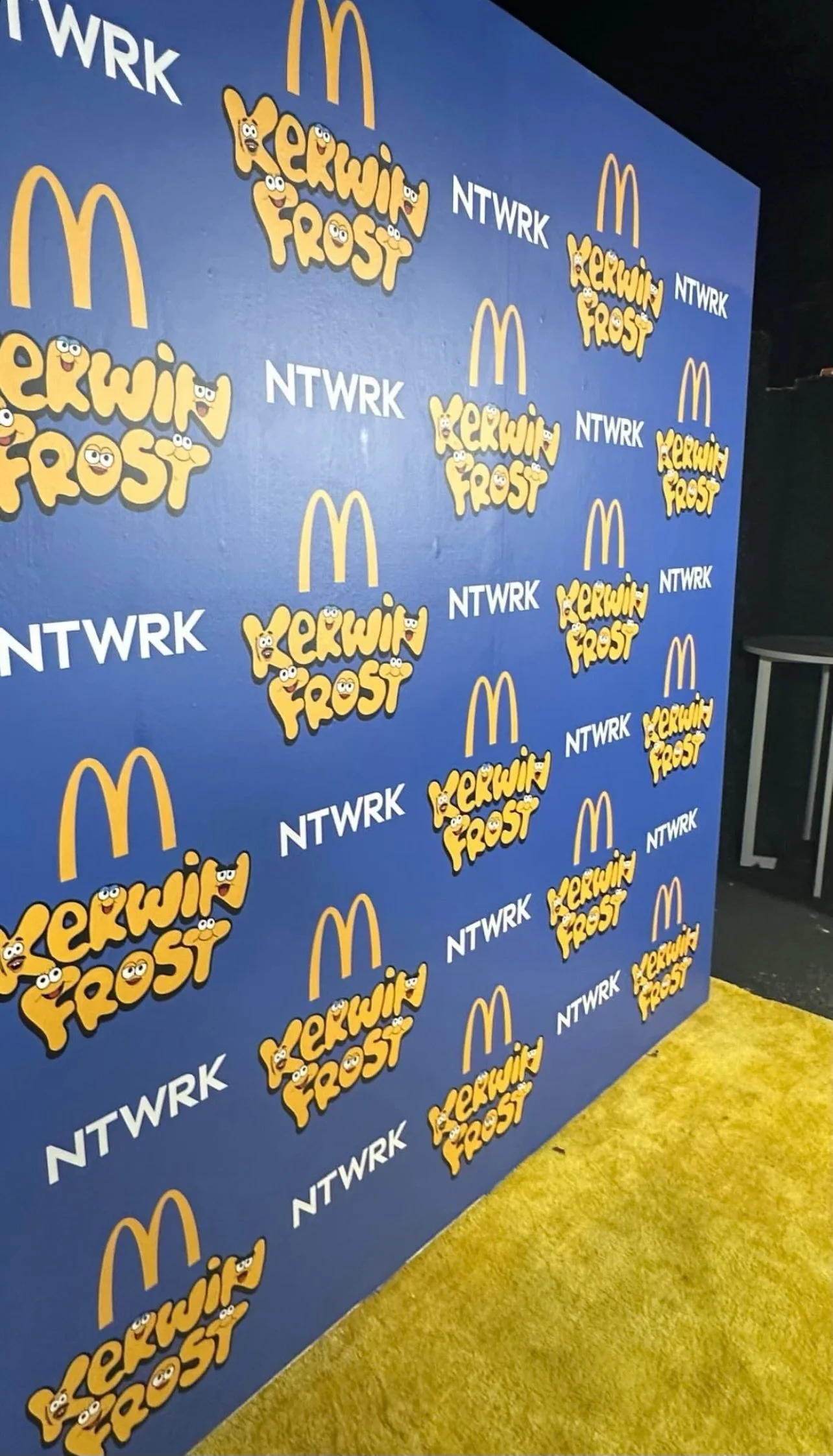 Kerwin Frost and McDonald's event backdrop with NTWRK branding, featuring logos on a blue and yellow background.