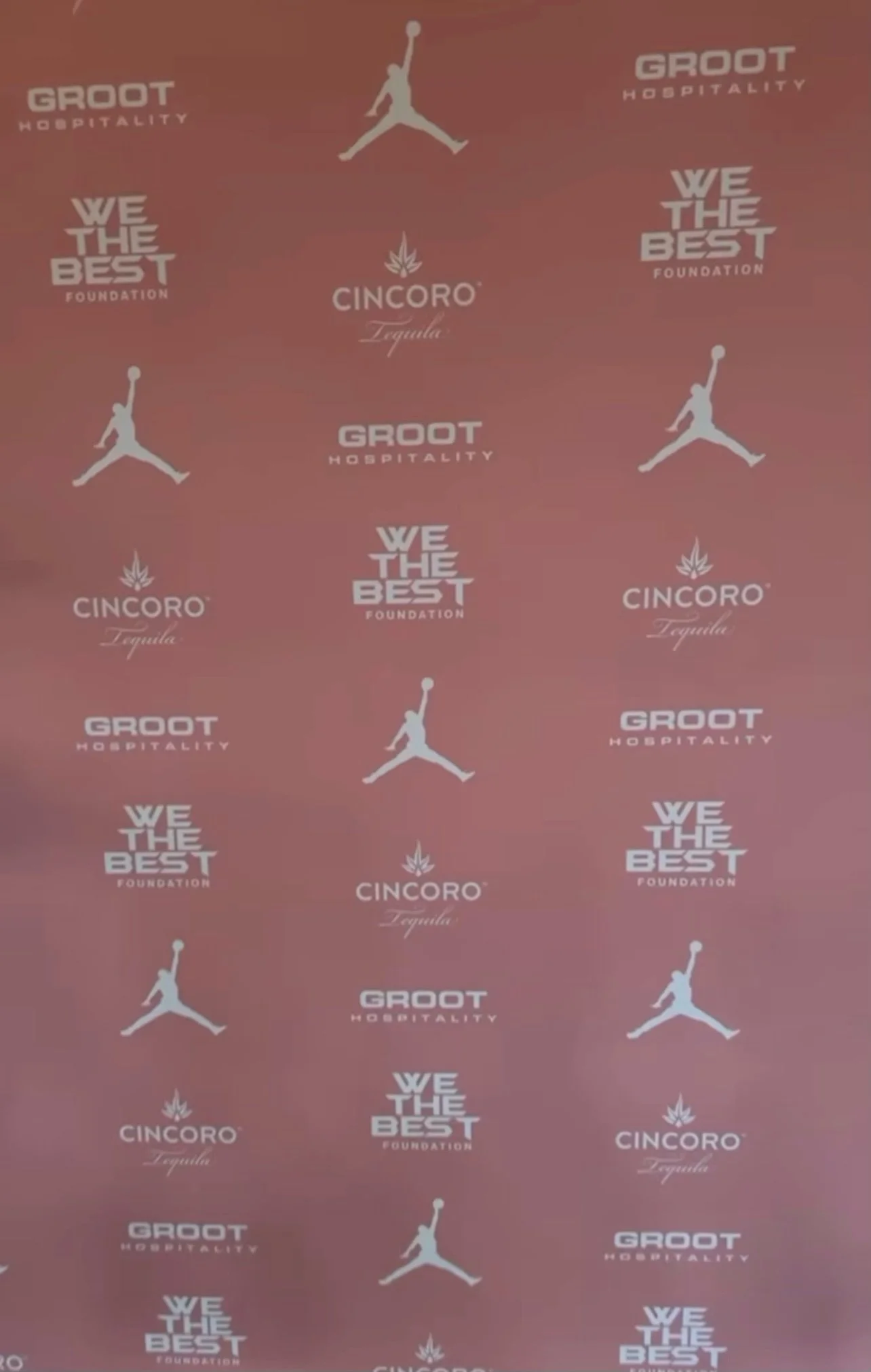 Red carpet backdrop with logos including Jordan Brand, Groot Hospitality, Cincoro Tequila, and We The Best Foundation.