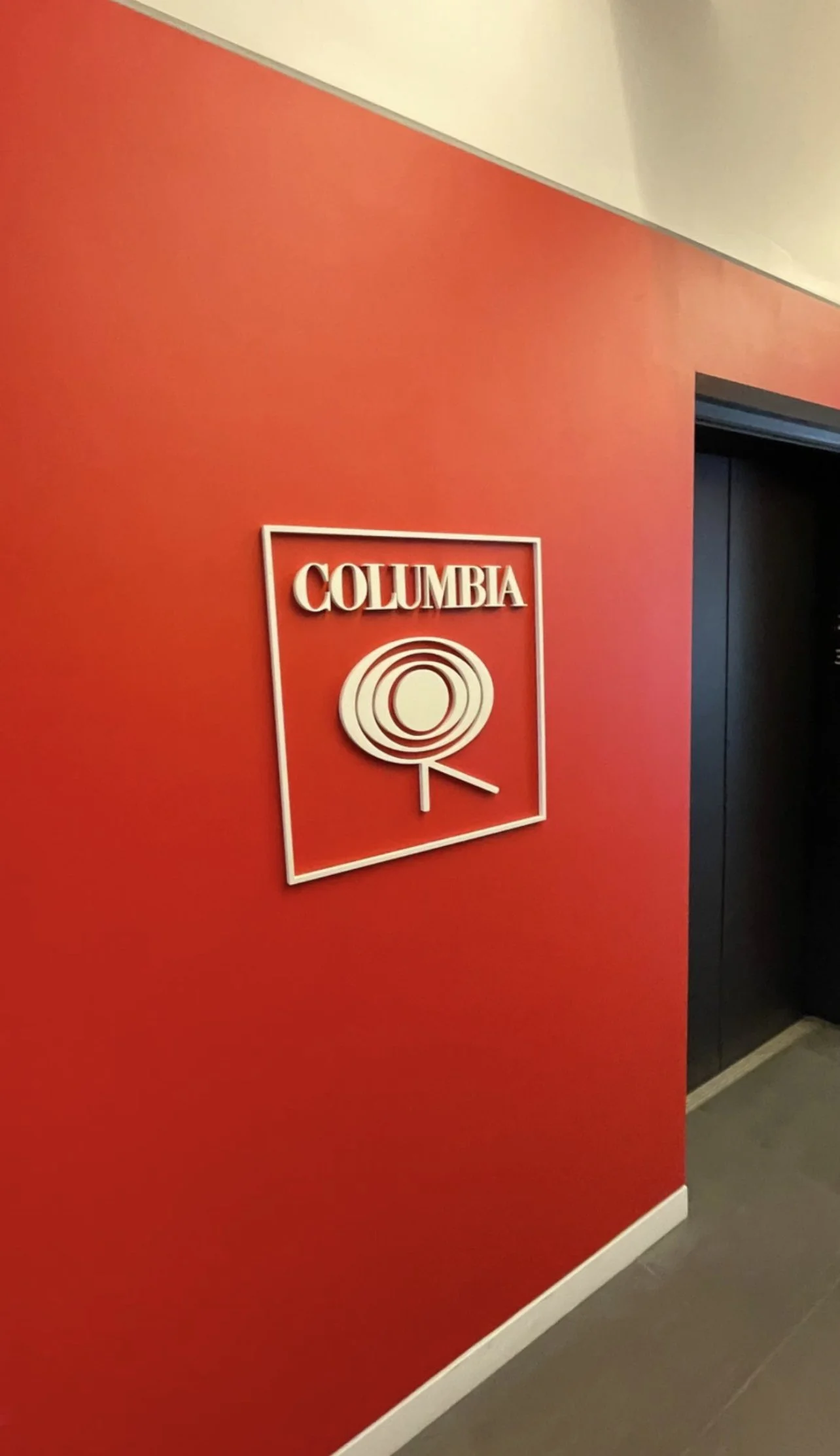 Red wall with Columbia logo near elevator doors
