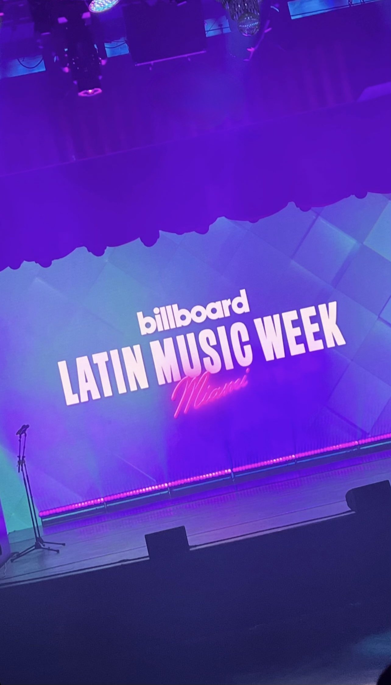 Stage setup for Billboard Latin Music Week in Miami with purple lighting and a microphone stand.