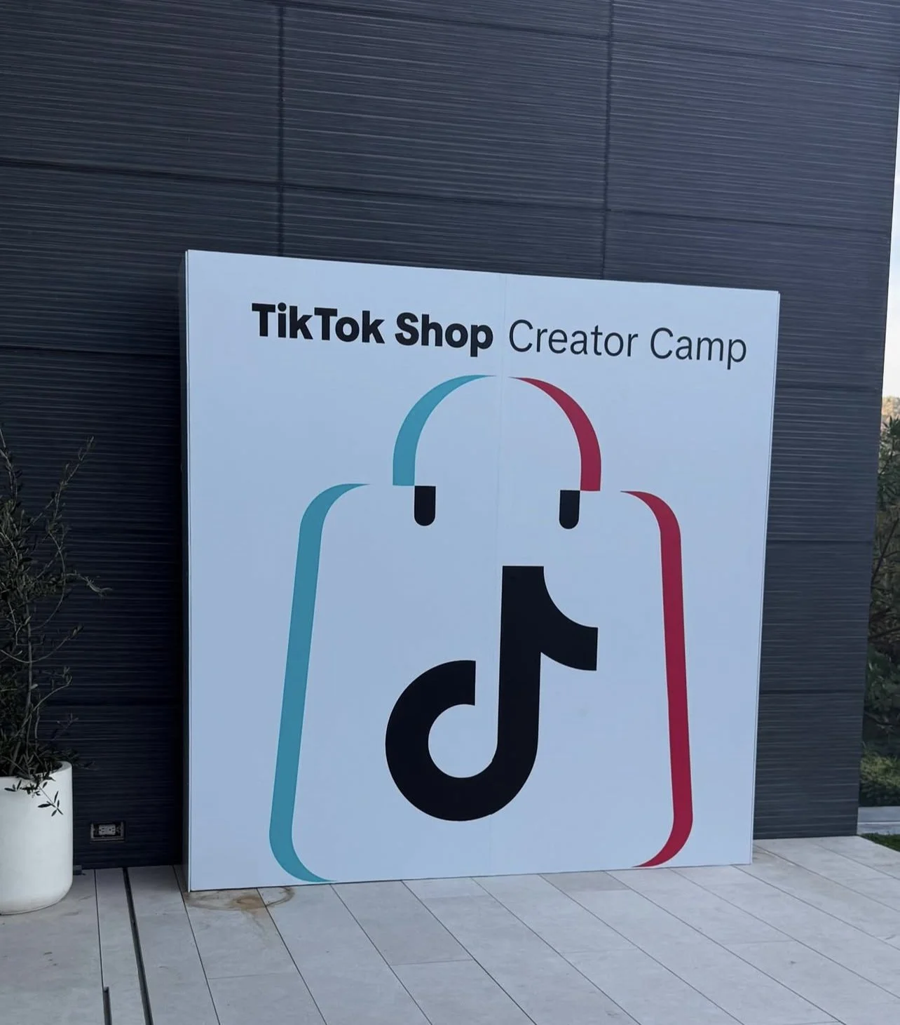 Sign for TikTok Shop Creator Camp with logo on a wall.