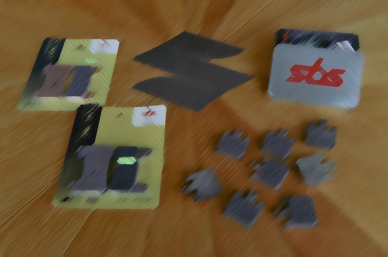 Auf einem Holztisch liegen Spielkarten, schwarze Karten und mehrere kleine graue Gegenstände, die möglicherweise Spielsteine sind.