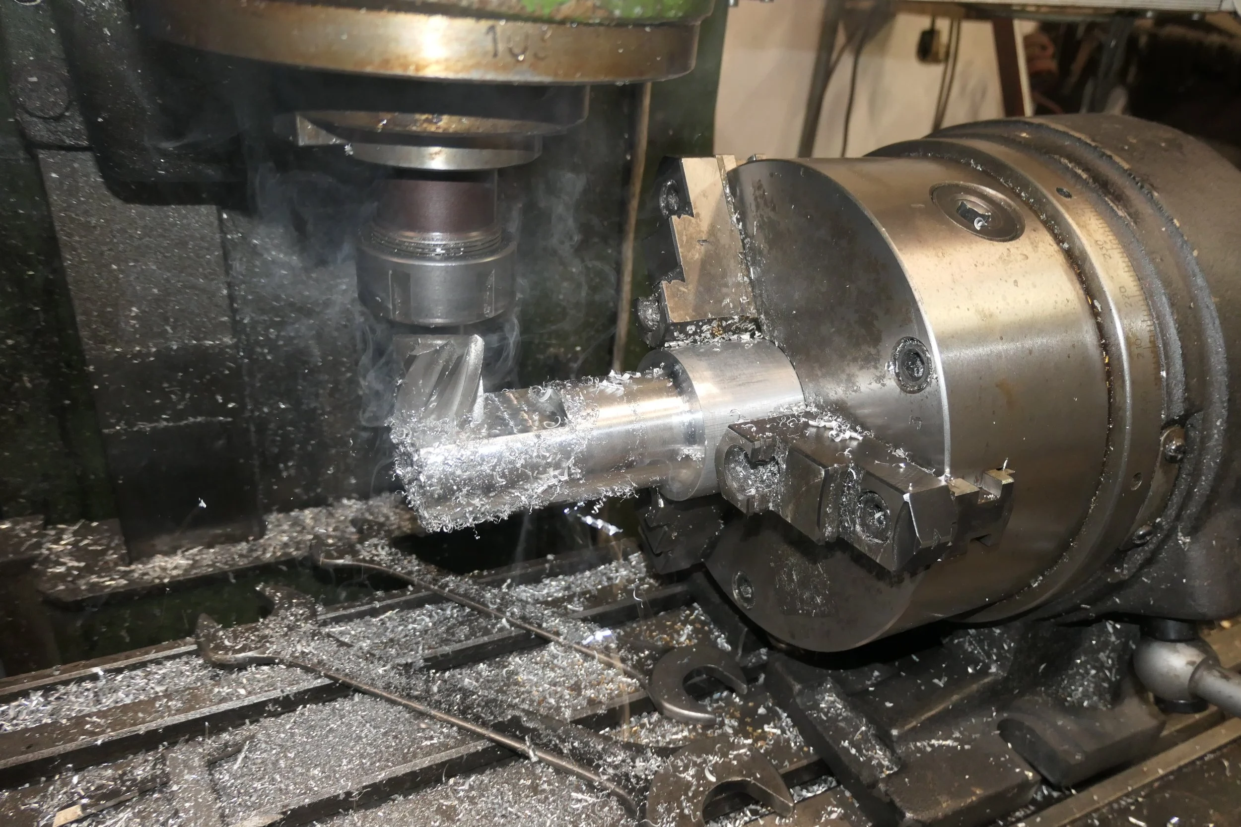 Eine CNC-Maschine fräst an einem metallischen Werkstück, Funken und Späne sind sichtbar.