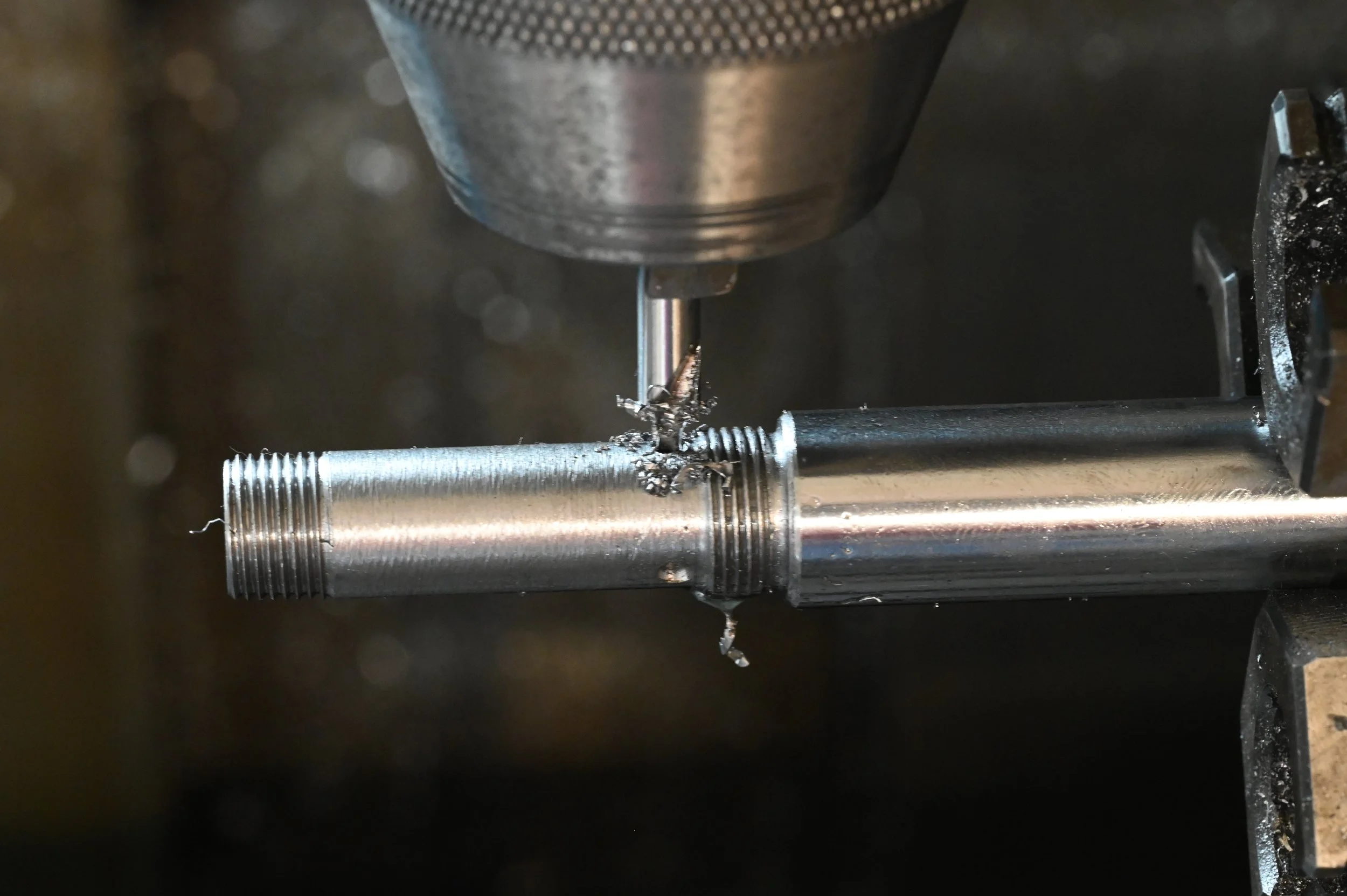 Metallarbeit beim Fräsen eines Metallrohrs auf einer Maschine, die Späne erzeugt.