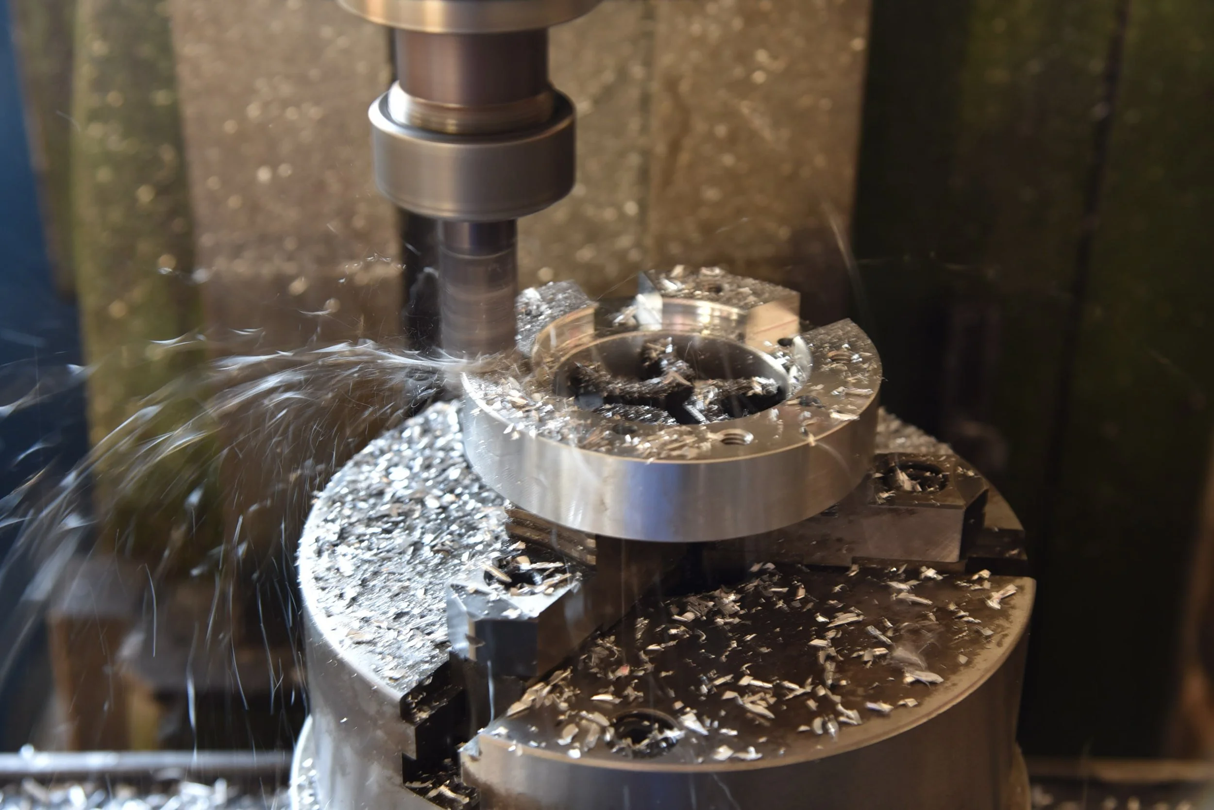 Fräsmaschine beim Bearbeiten eines metallischen Werkstücks, dabei entstehen Späne und Funkenflug.