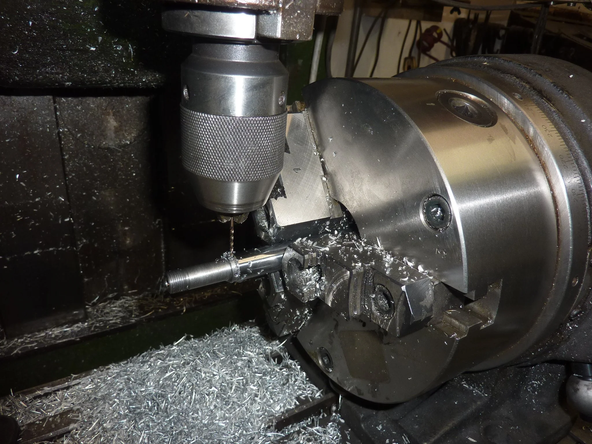 Nahaufnahme einer Metallmaschine, vermutlich ein Drehmaschinenwerkzeug, im Arbeitsprozess, mit Metallspänen auf dem Tisch.