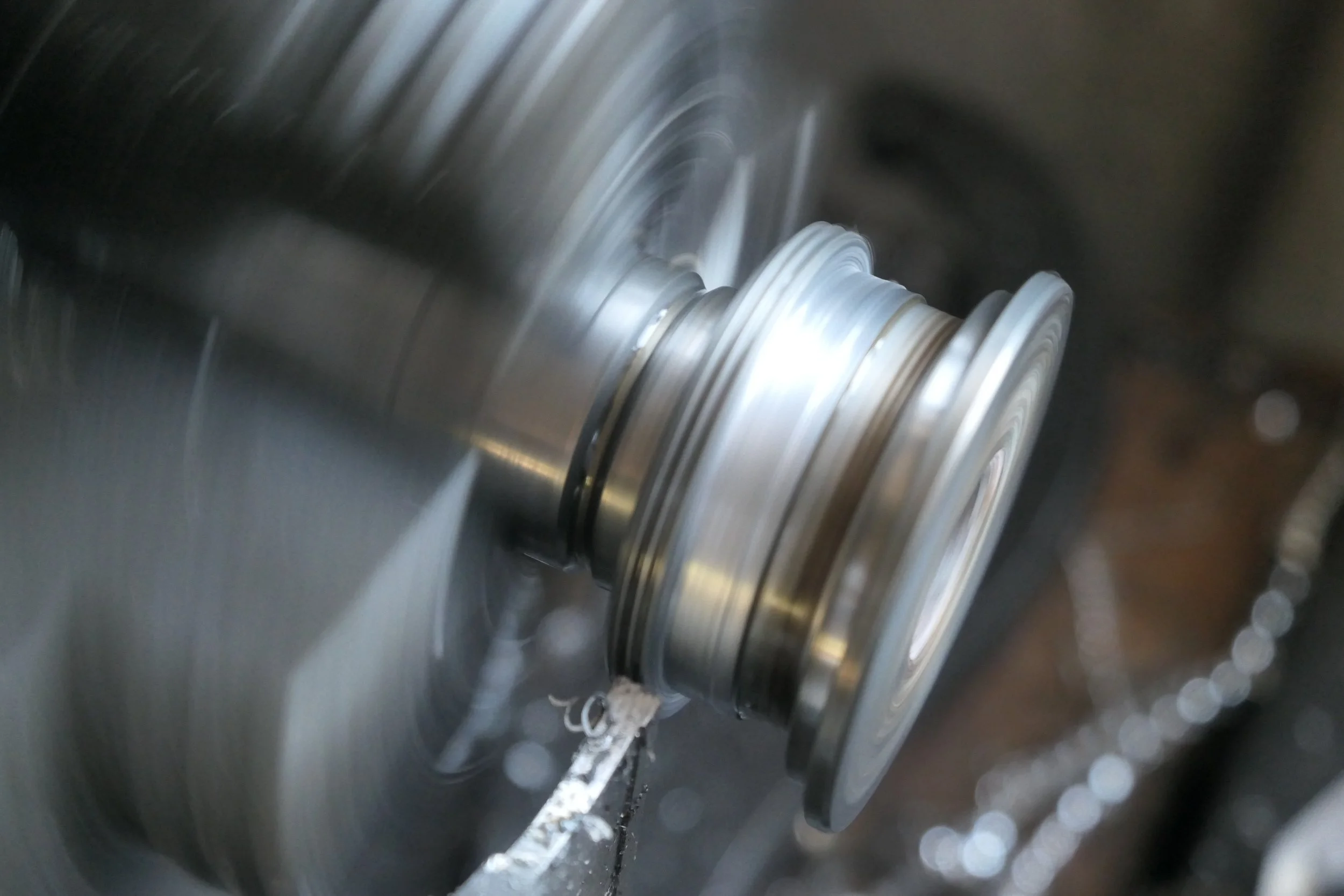 Nahaufnahme eines rotierenden Metallteils in einer Maschine, vermutlich eine CNC-Maschine, mit sichtbaren Spuren von Bearbeitung und Metallspänen