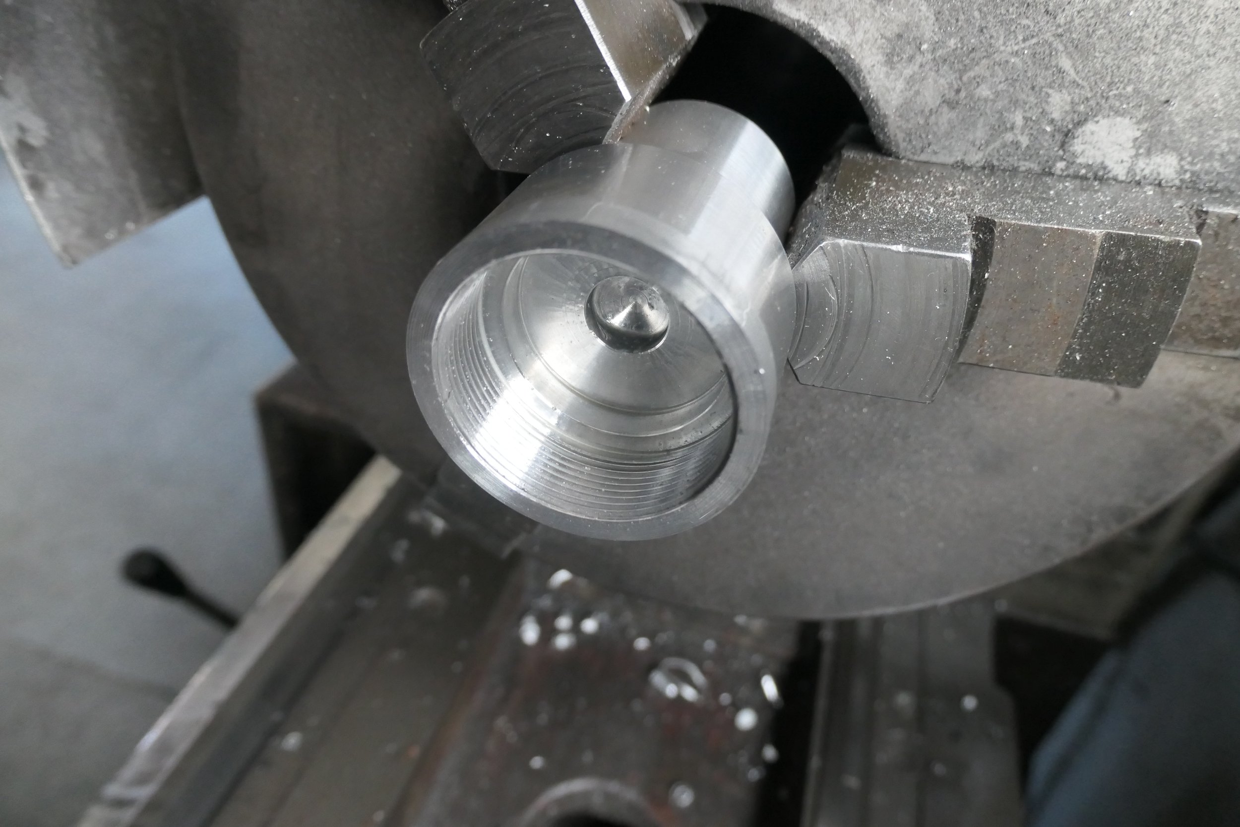 Metallteilaufnahme in einer Maschine, vermutlich beim Herstellungsprozess, mit sichtbaren Schneide- oder Fräsmarkierungen.