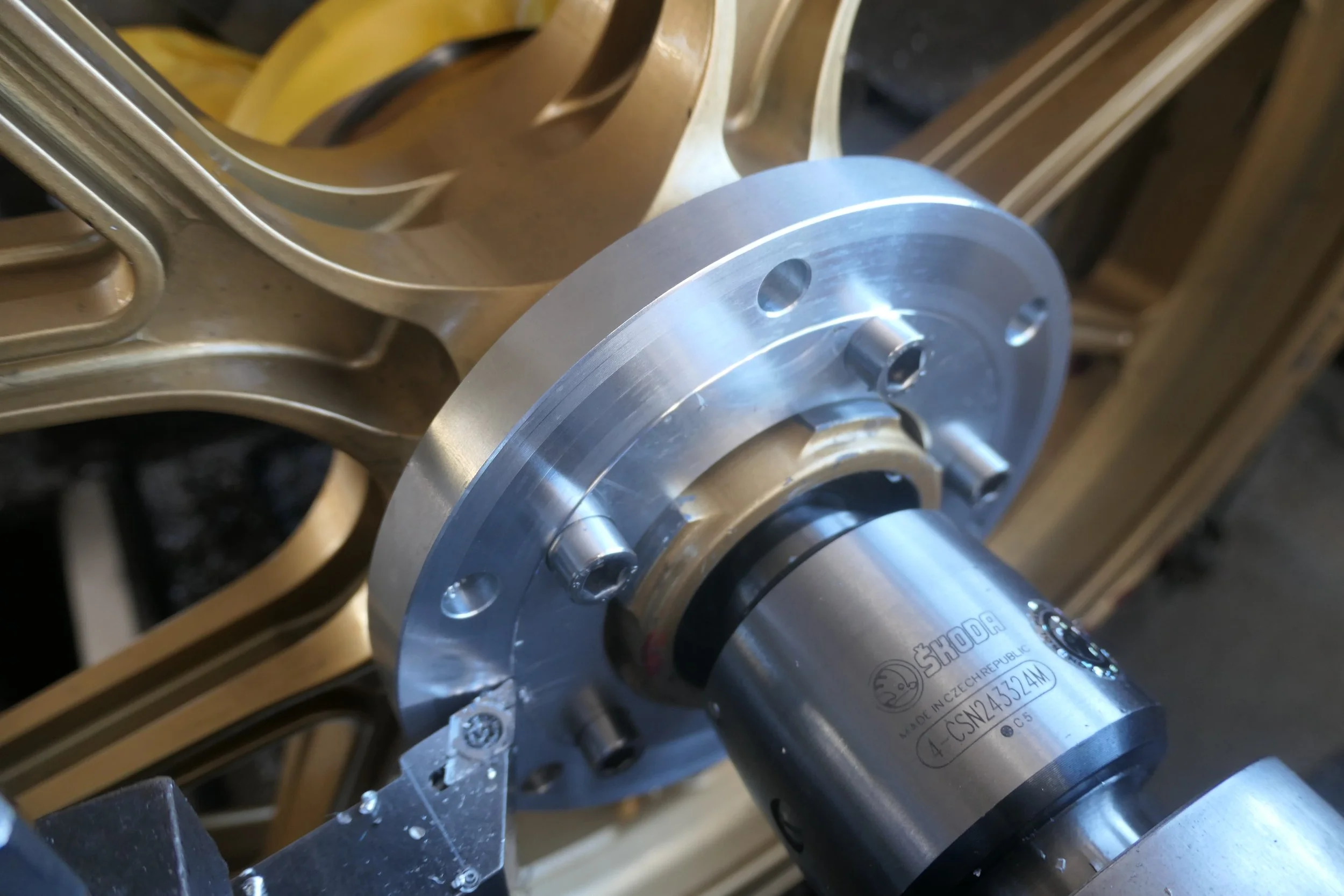 Nahaufnahme eines metallischen Getriebeteils, das auf einer Maschine montiert ist, mit sichtbaren Schrauben und Lagermechanismus.