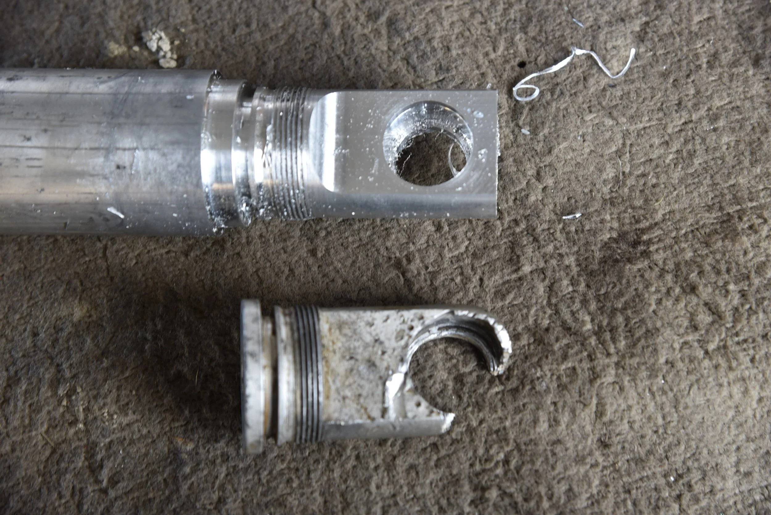 Zwei zerbrochene Metallrohre mit Gewinden auf einem Boden