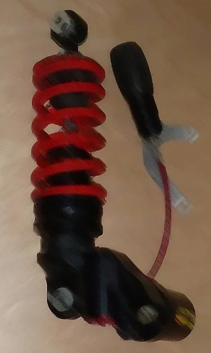 Fahrwerk mit roter Feder, Stoßdämpfer und Kabel, auf Holzboden.