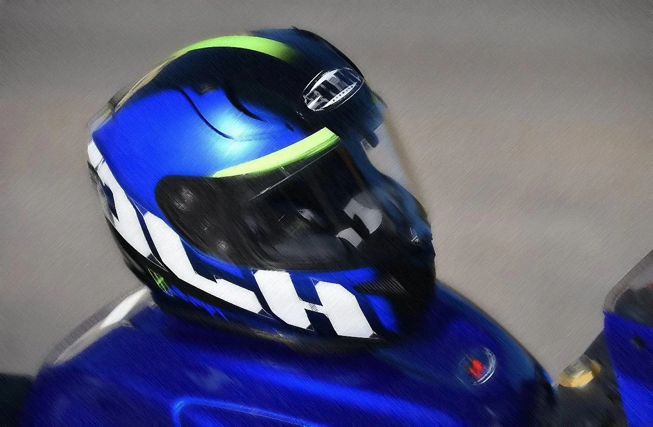 Motorradfahrer mit blauer Rüstung und Helm, der mit hoher Geschwindigkeit auf der Straße fährt.