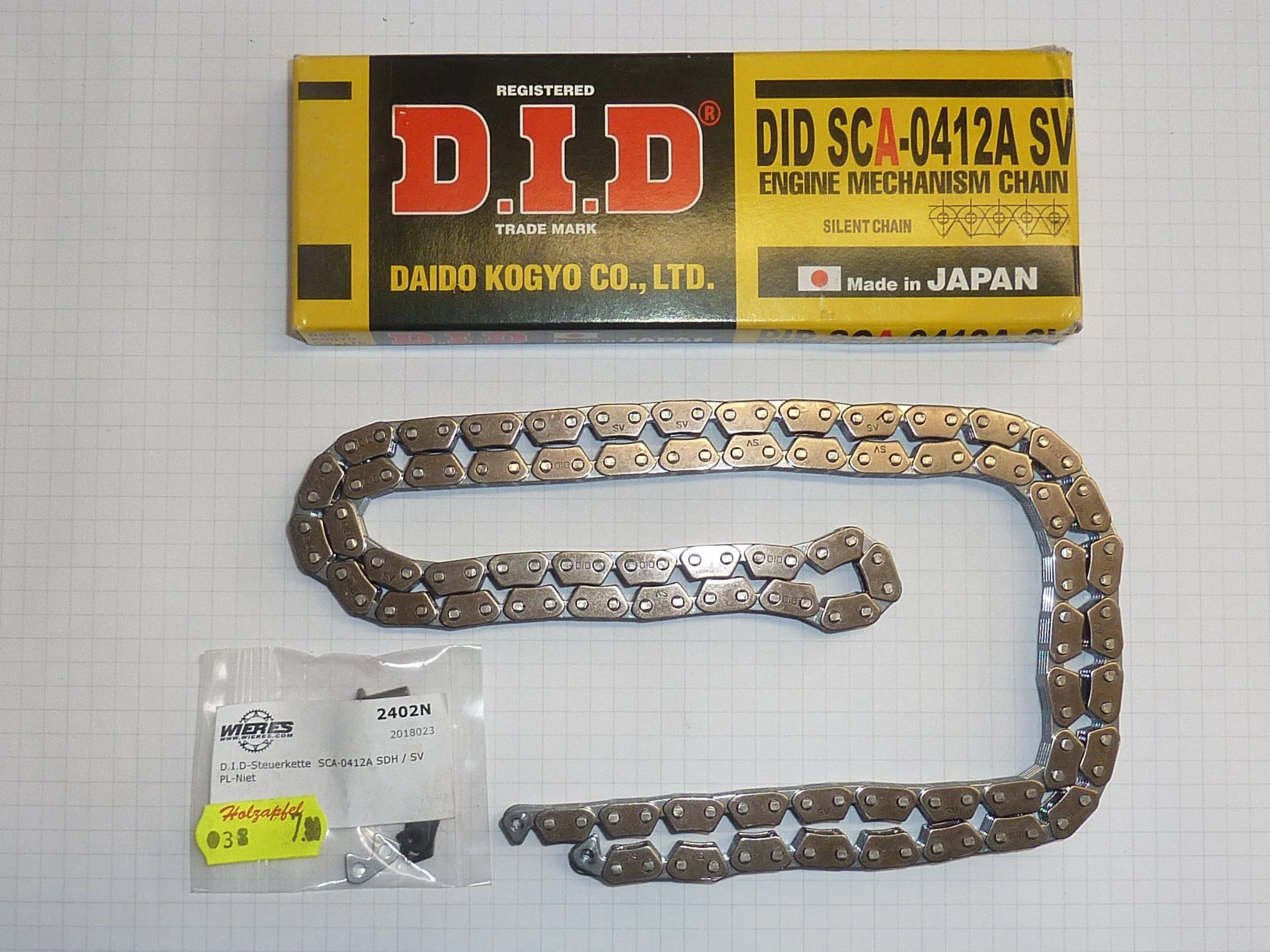 Kettensatz für Motor, bestehend aus Metallkette, Verpackung, und einem kleinen Teil in Plastiktüte