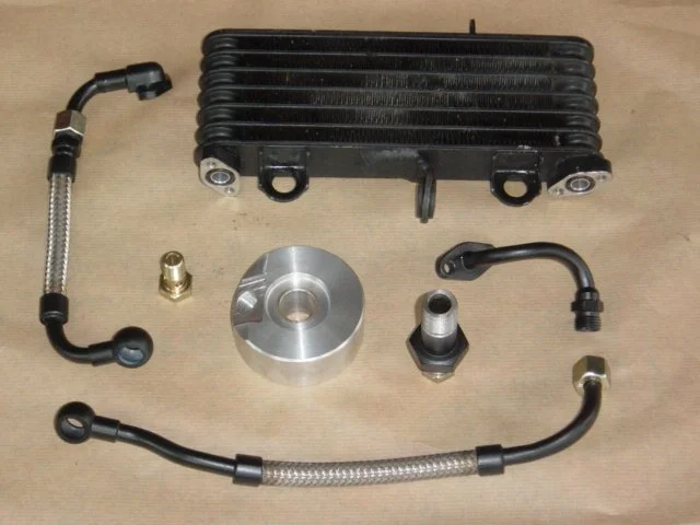 Ein Motorrad-Ladeluftkühler mit verbundenen Sensoren, Schrauben und Metallkomponenten auf einer Holzoberfläche.