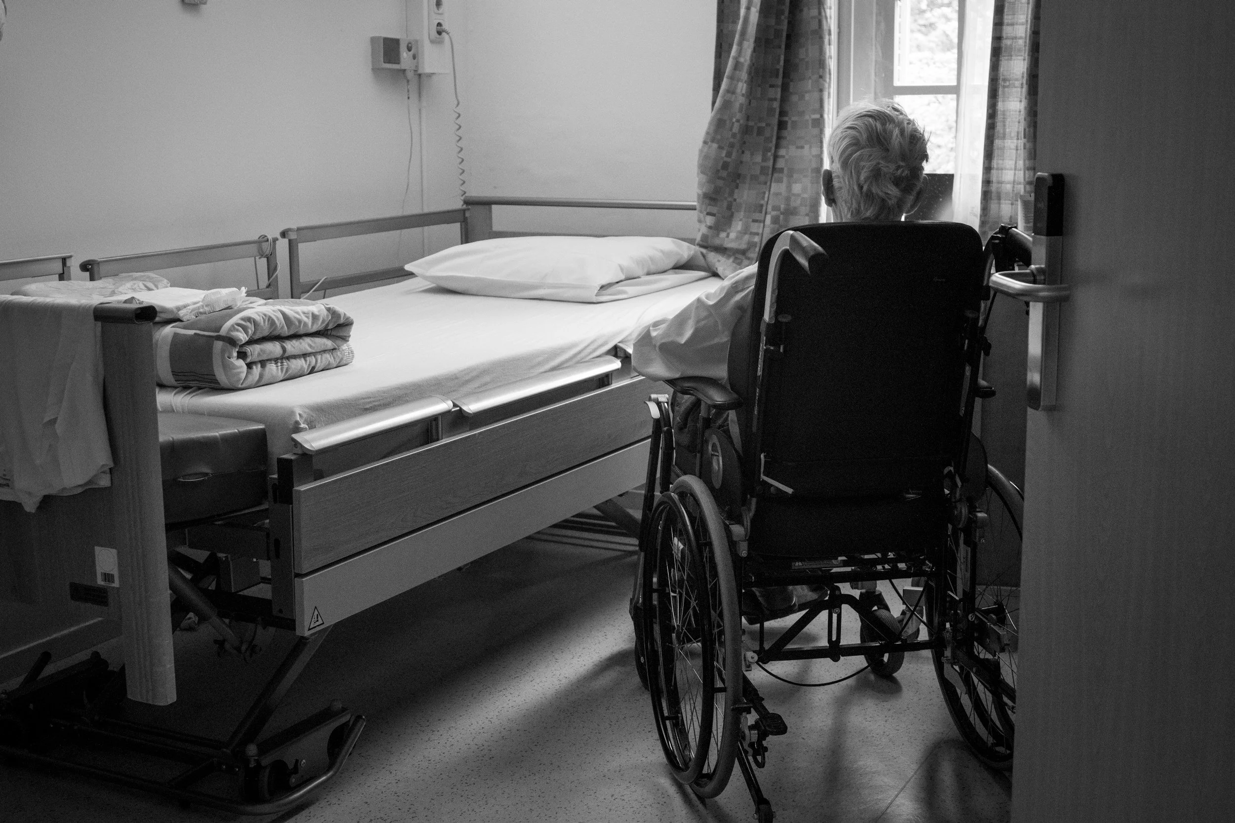 elderly person sitting alone in a nursing home room