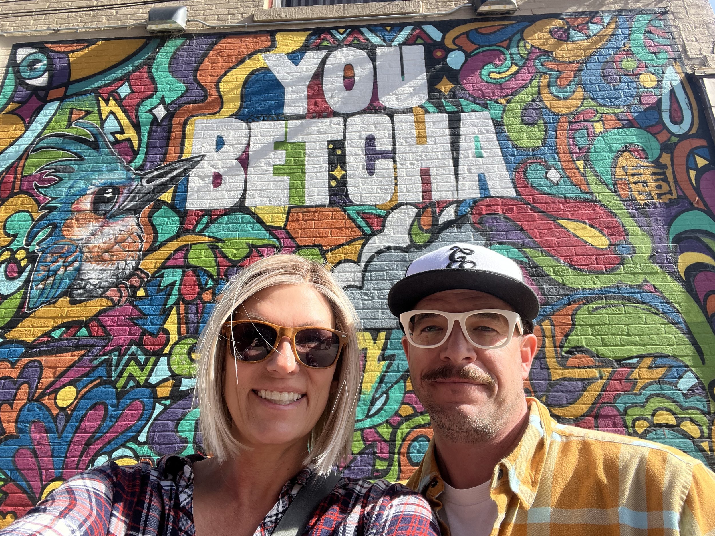 Erik and Teresa standing in front of graffiti
