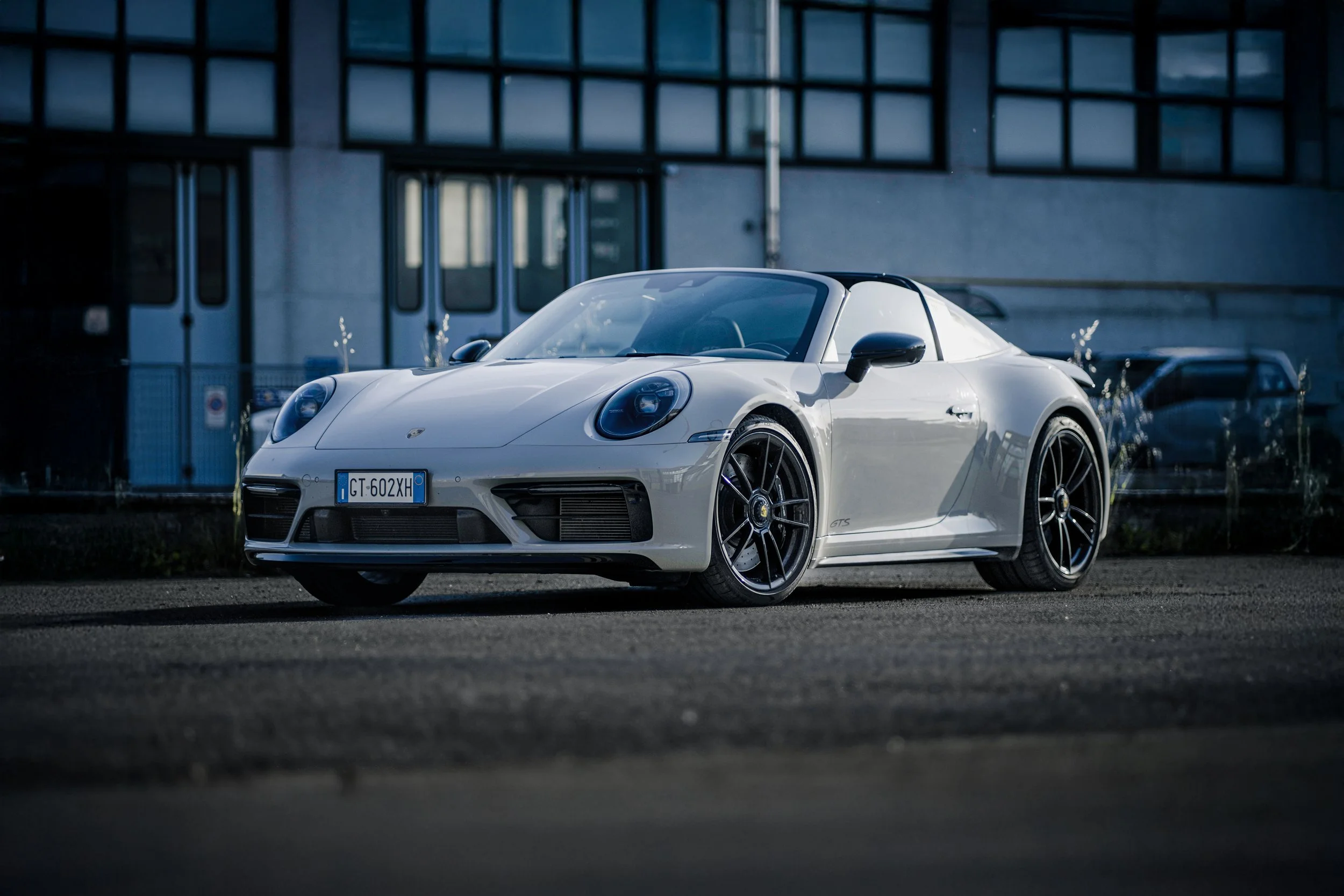 Auto sportiva Porsche 911 Carrera GTS bianca parcheggiata in un'area urbana, scattata al crepuscolo.