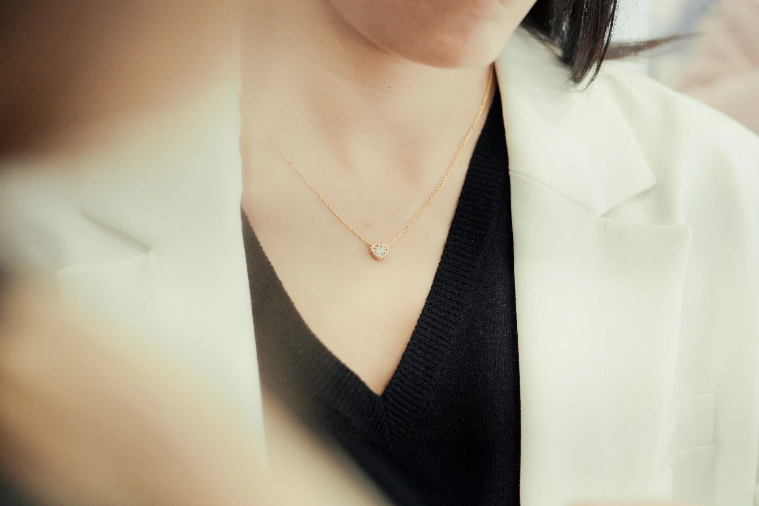 Collana d'oro con cuore decorato di pietre preziose indossata da una donna.