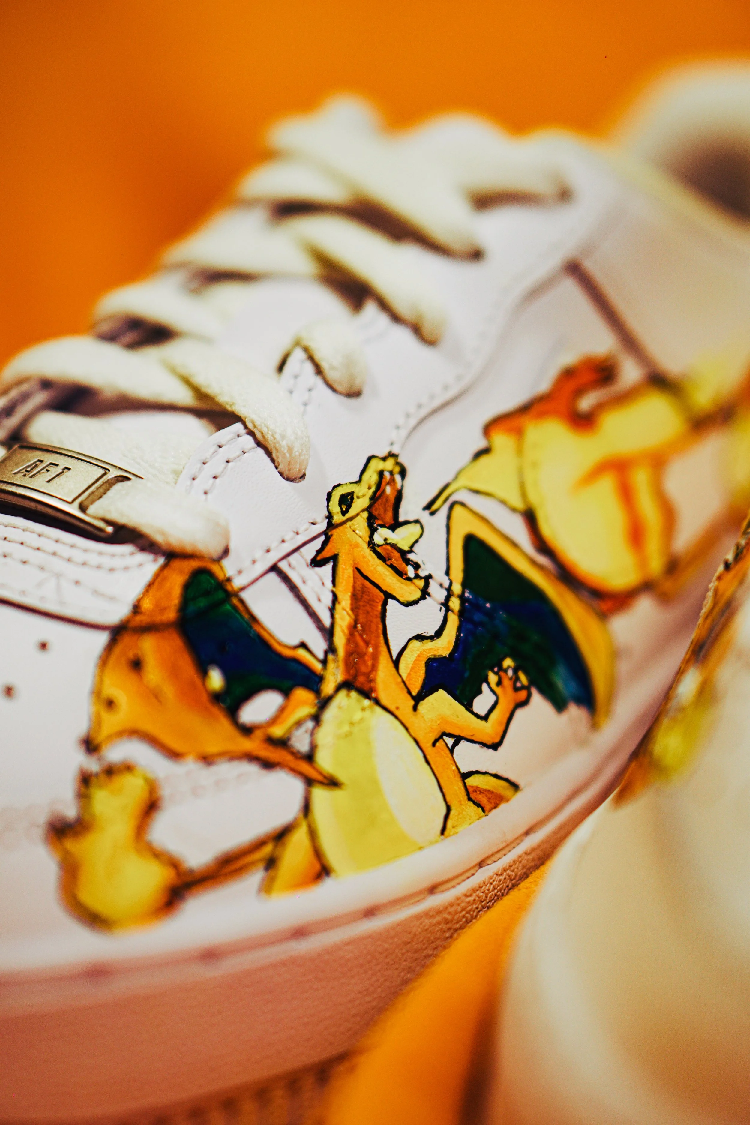 Scarpa bianca con disegno di un drago giallo e arancione con ali blu