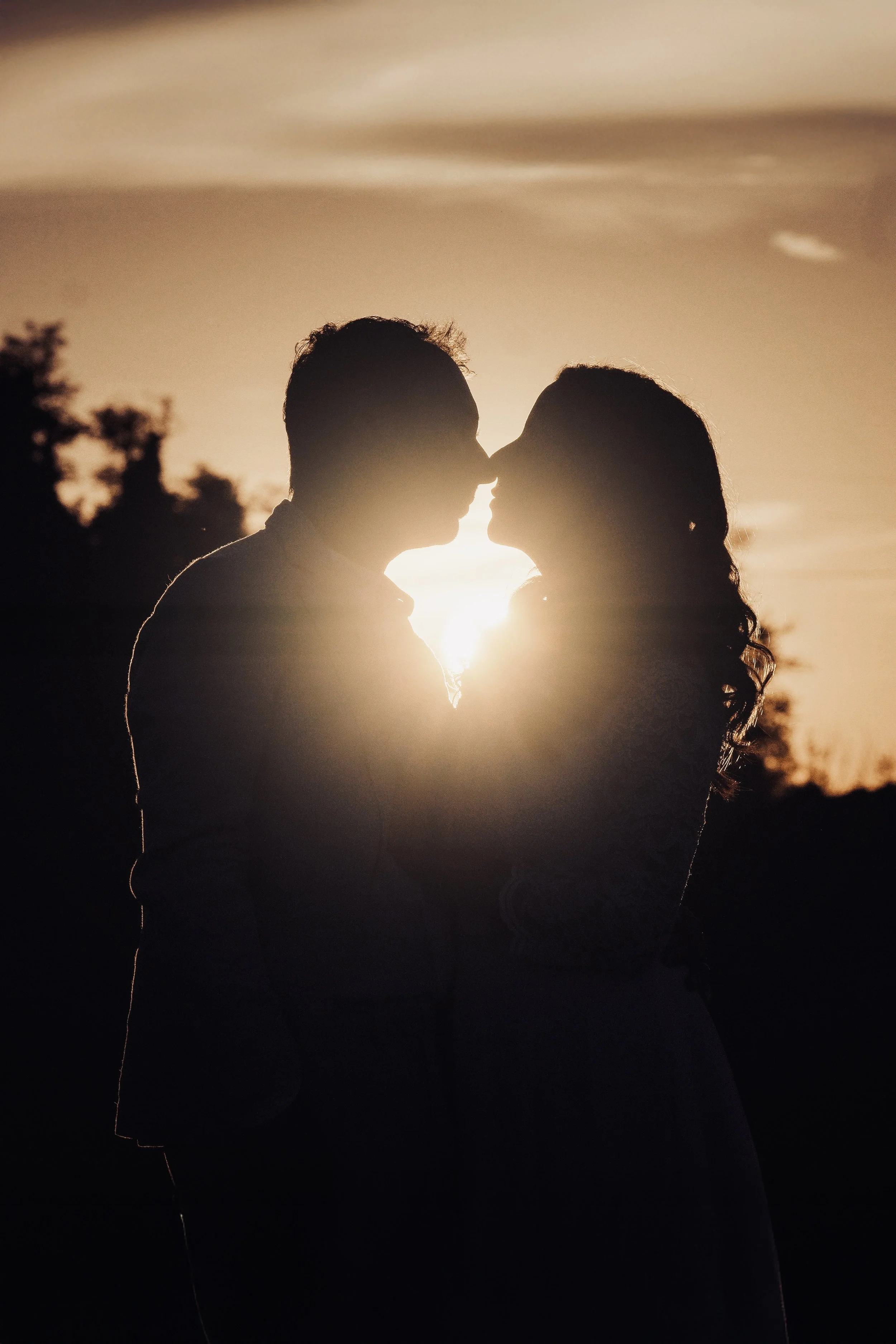Silhouette di una coppia che si bacia al tramonto con lo sfondo del sole che tramonta.