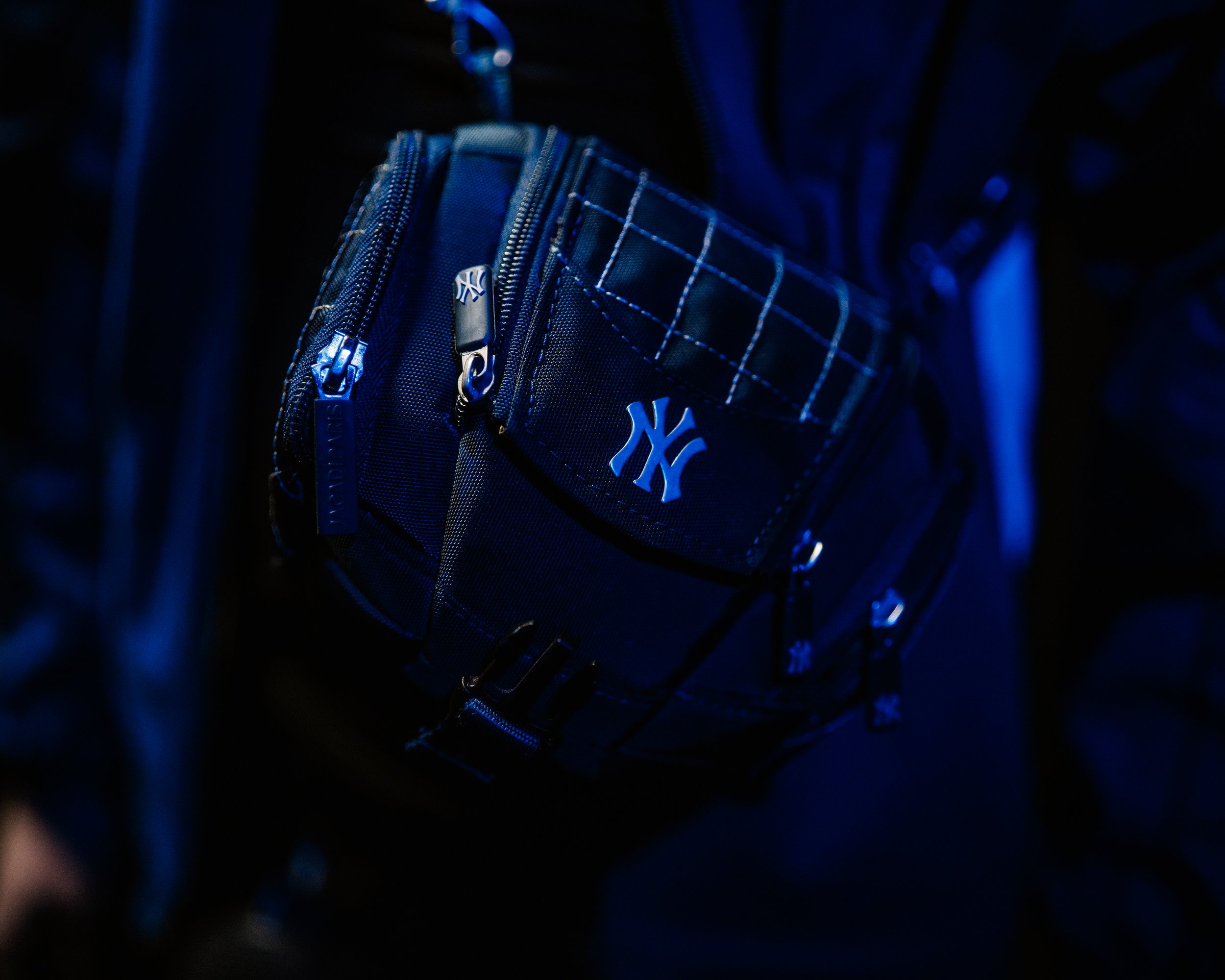 Zaino nero con dettagli blu, logo NY di New York Yankees in metallo, cerniere e tasche visibili.