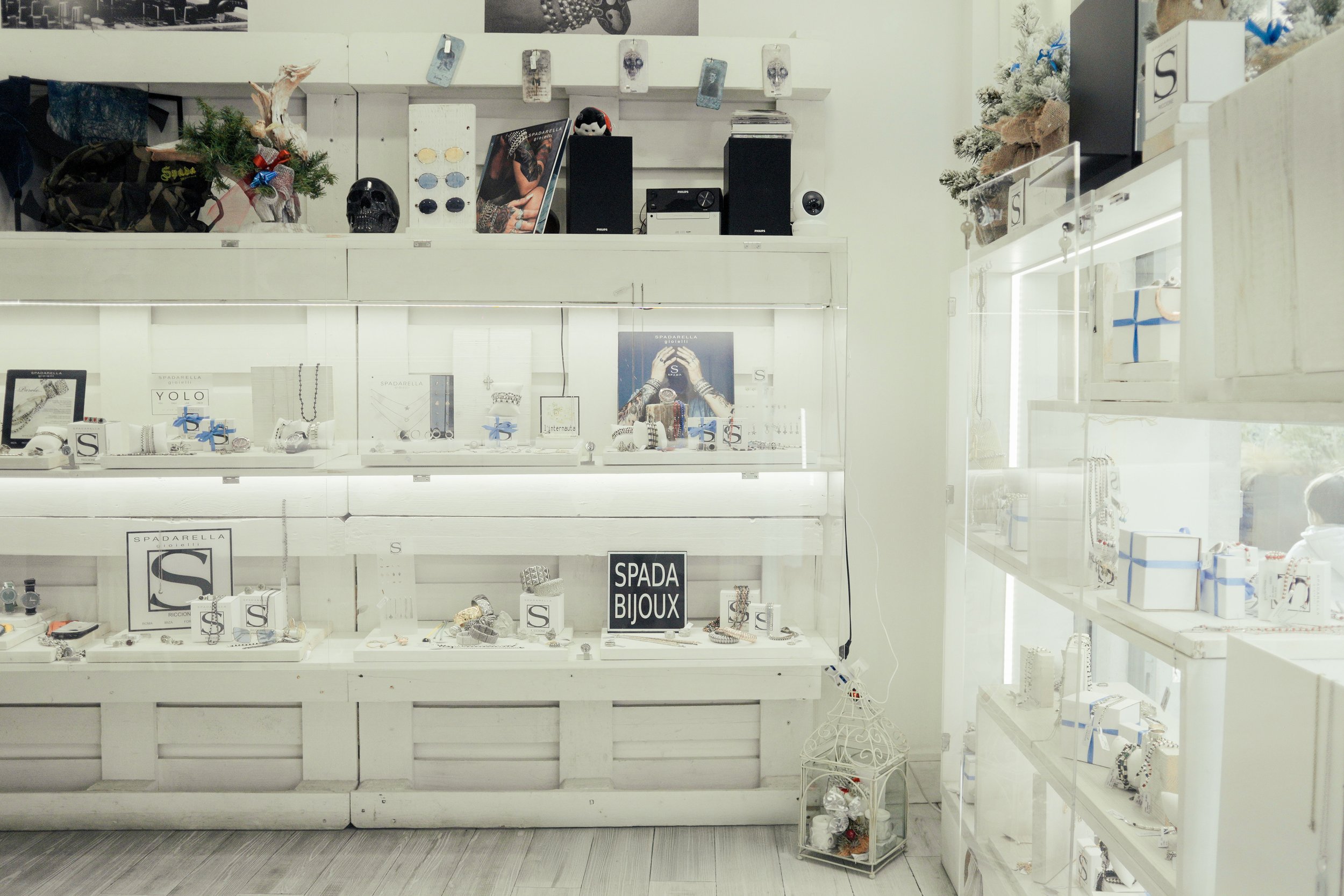 Interno di un negozio di gioielli con espositori di bijoux in bianco e scaffali con decorazioni natalizie.