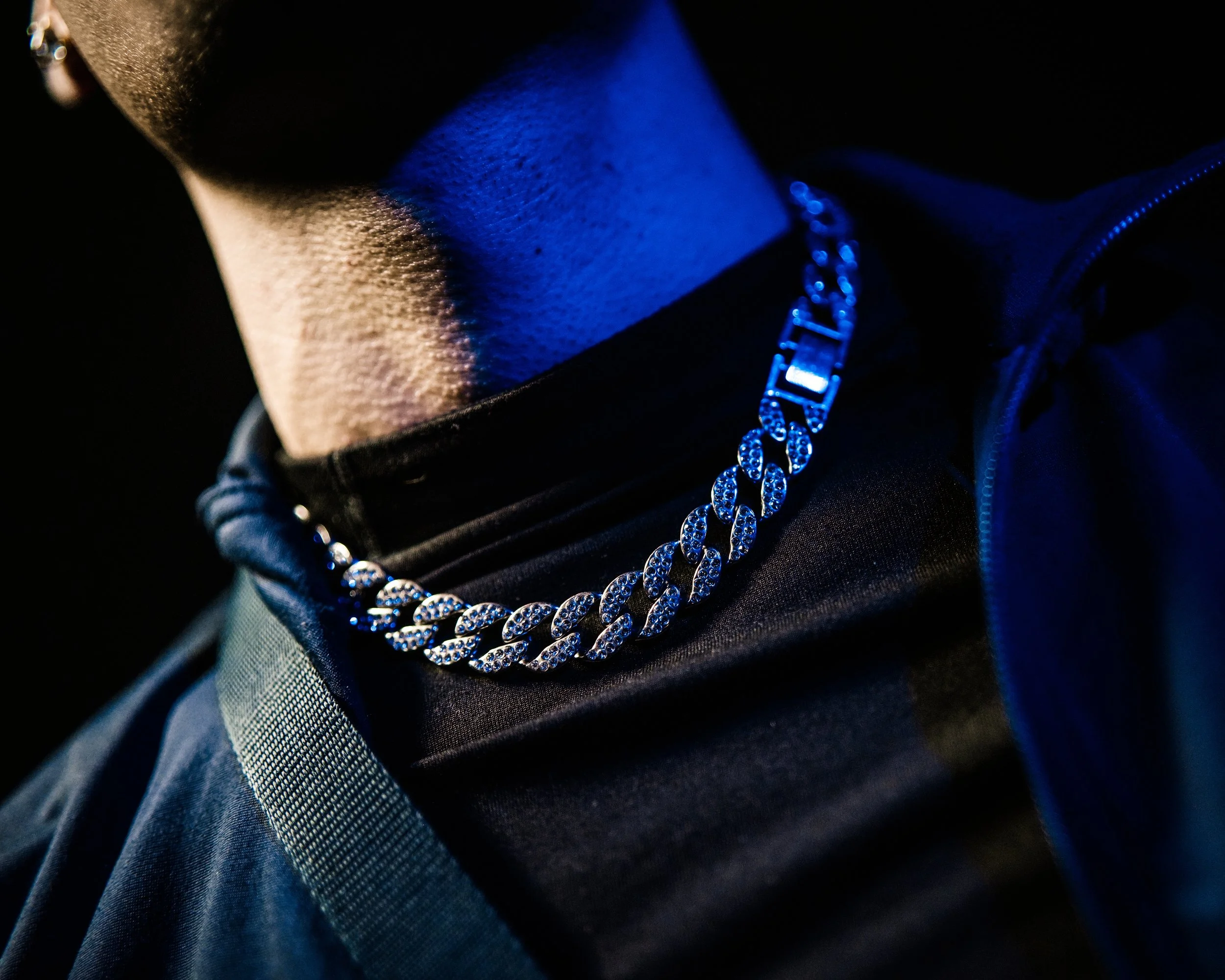 Girocollo argentato con pietre luccicanti indossato da una persona con indumenti neri e cappotto.