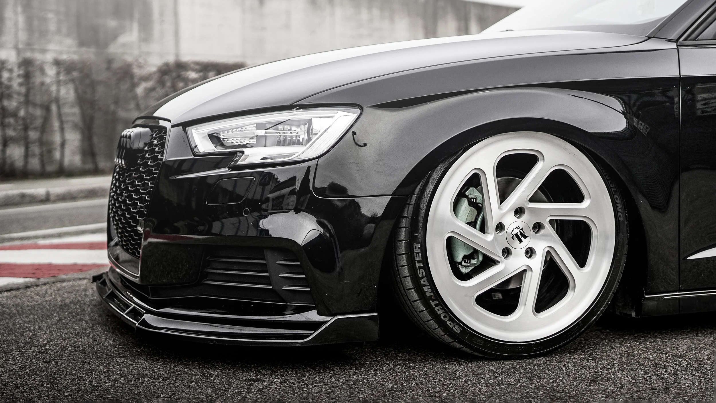 A 2020 black Audi S4 parked on a race track with white alloy wheels and green brake calipers.