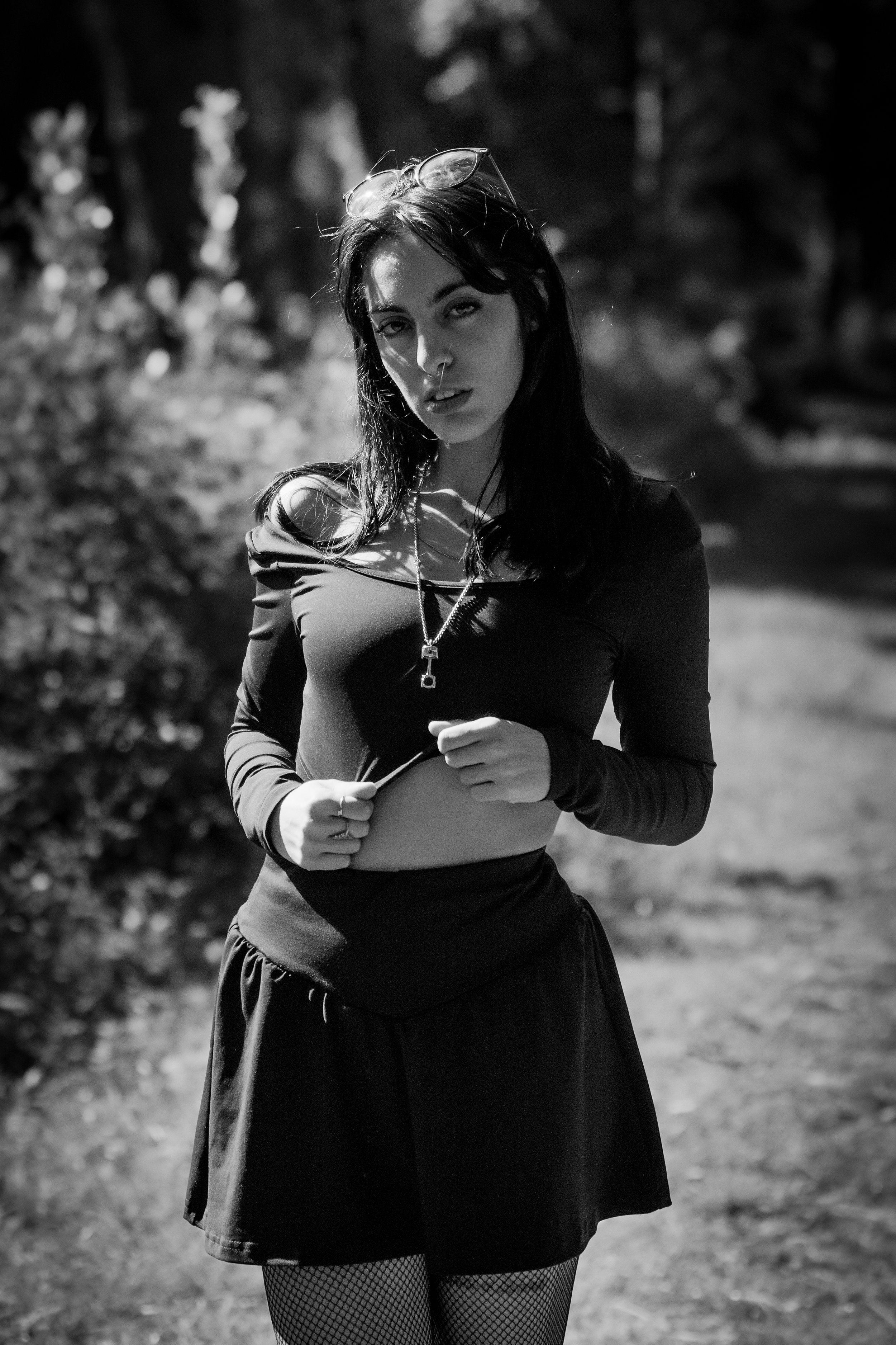 Ragazza con cappuccio e minigonna in un ambiente naturale, in bianco e nero.