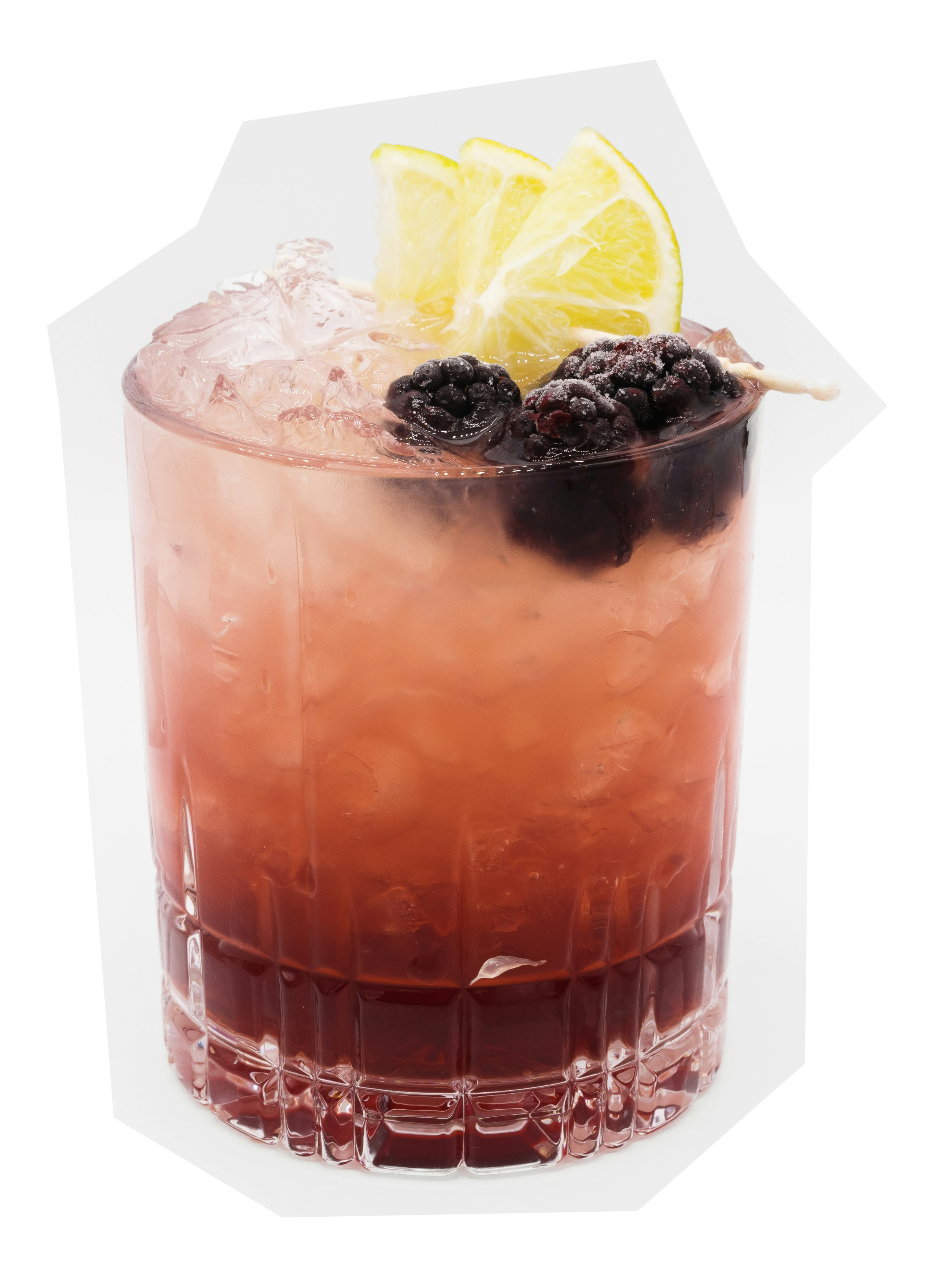 Glass with a pink cocktail, ice, blackberries, and lemon slice garnish.