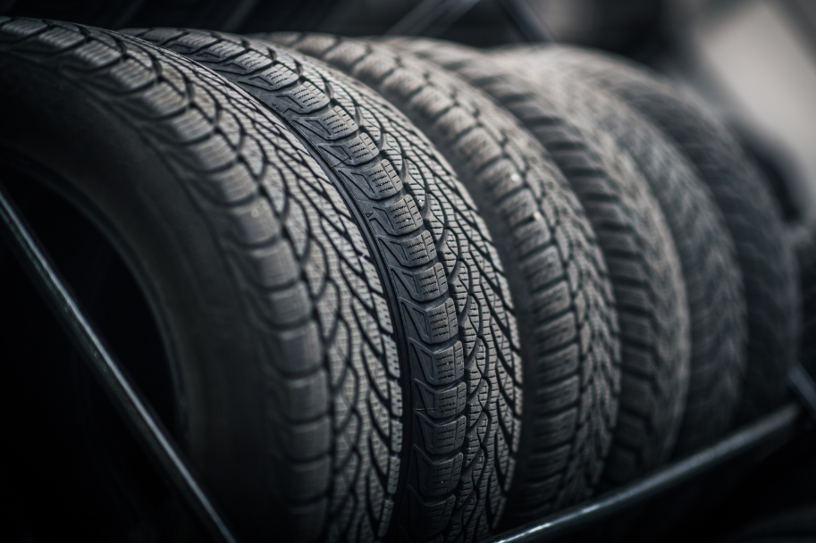 Close-up of four car tires stacked, showing detailed tread patterns.