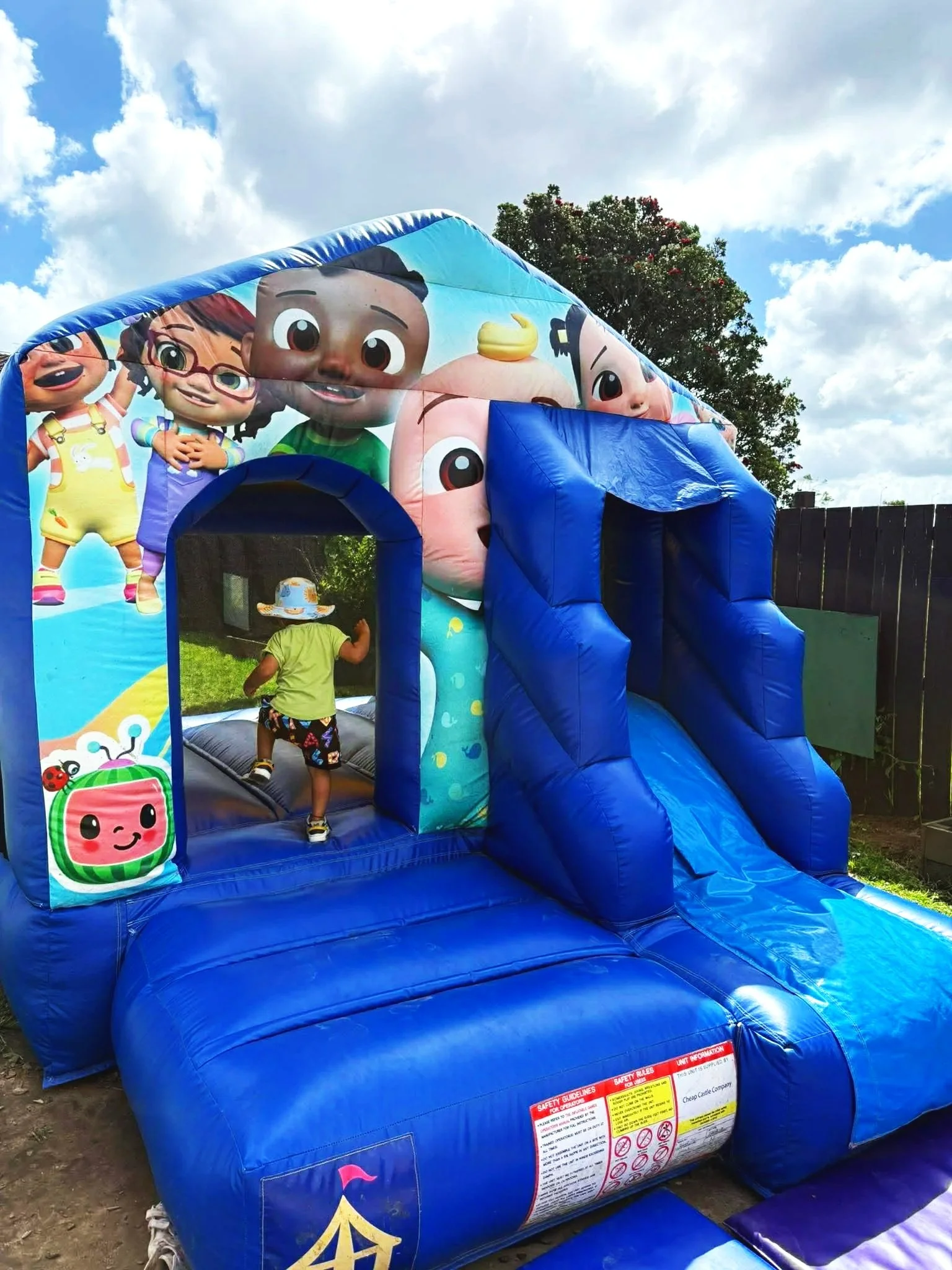 Colorful inflatable bounce house featuring Mickey Mouse and Minnie Mouse with a slide, set up outdoors on a backyard patio.