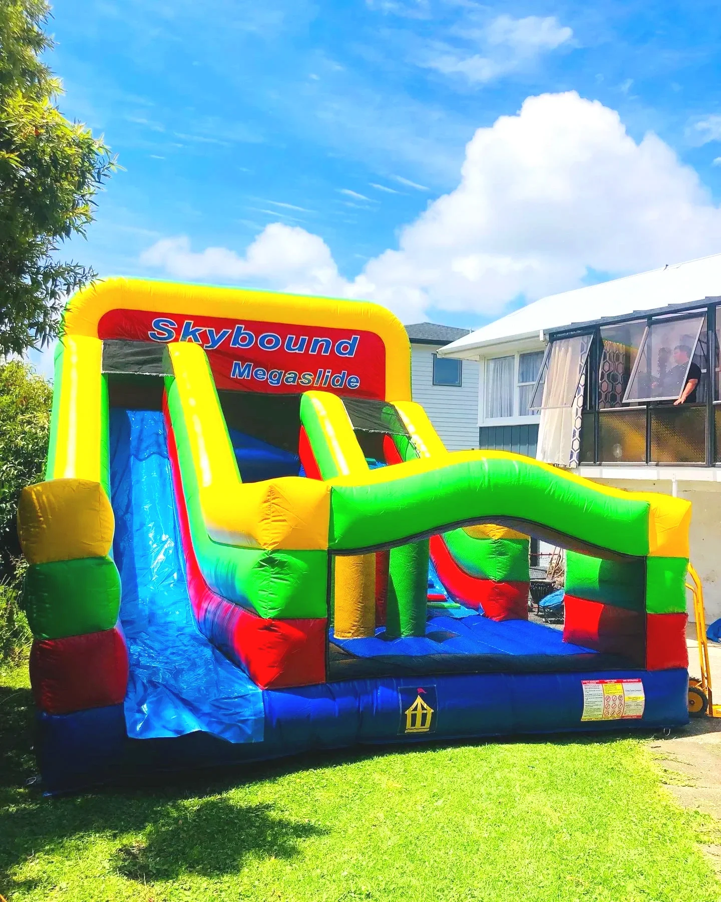 Children playing on a colorful inflatable bounce house that resembles a castle with yellow towers and red and blue accents.