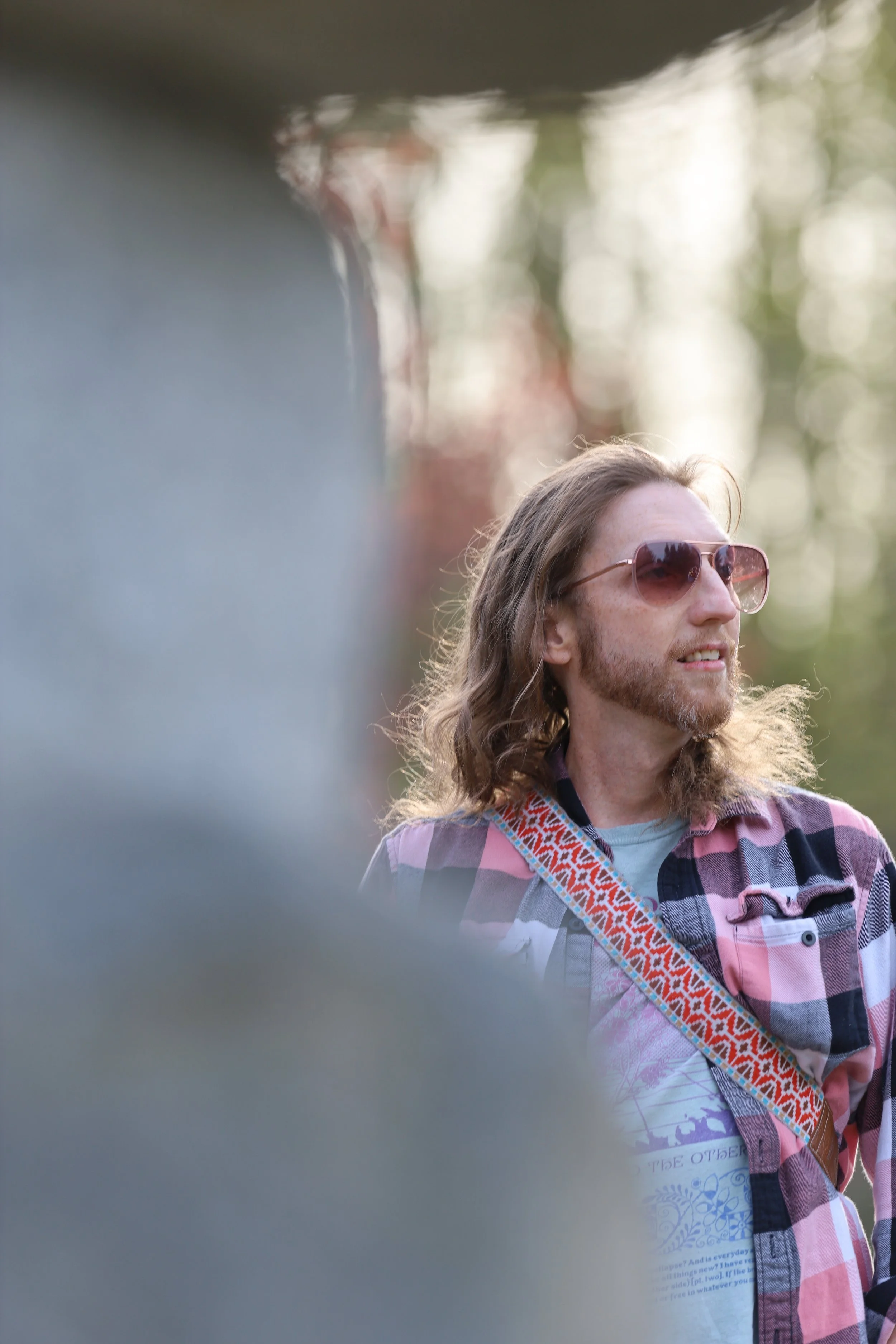 Man wearing sunglasses and a plaid shirt outdoors