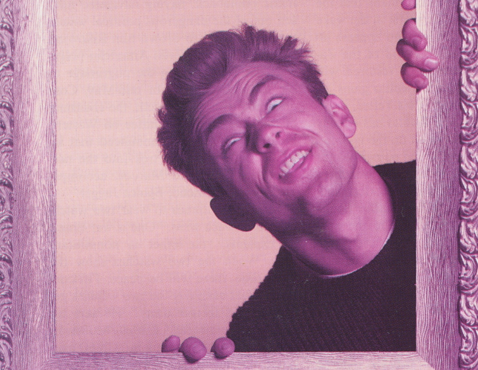 A man with exaggerated facial expression looking up, holding onto a pink-colored frame.