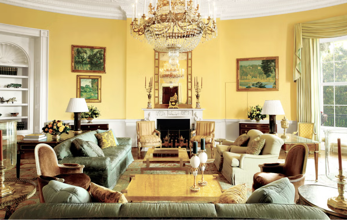 Elegant living room with yellow walls, ornate chandelier, fireplace, and classic furniture.