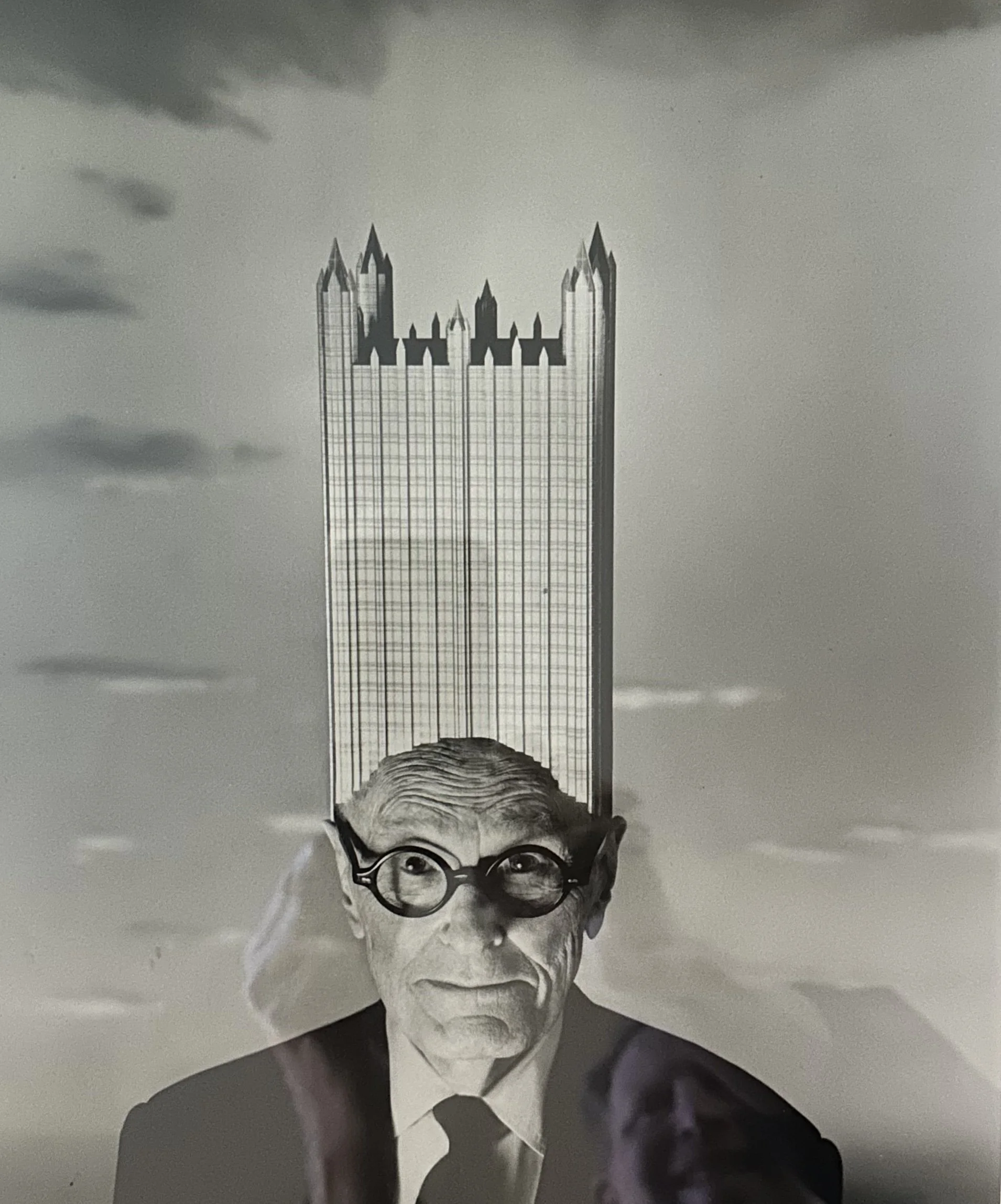 Black and white photograph of a man with glasses, wearing a suit and tie, with a serious expression. The image appears to be upside down.