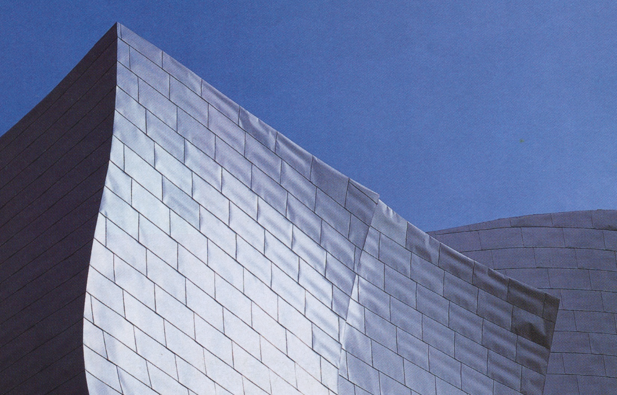 Close-up of modern building with reflective metal panels against a blue sky.
