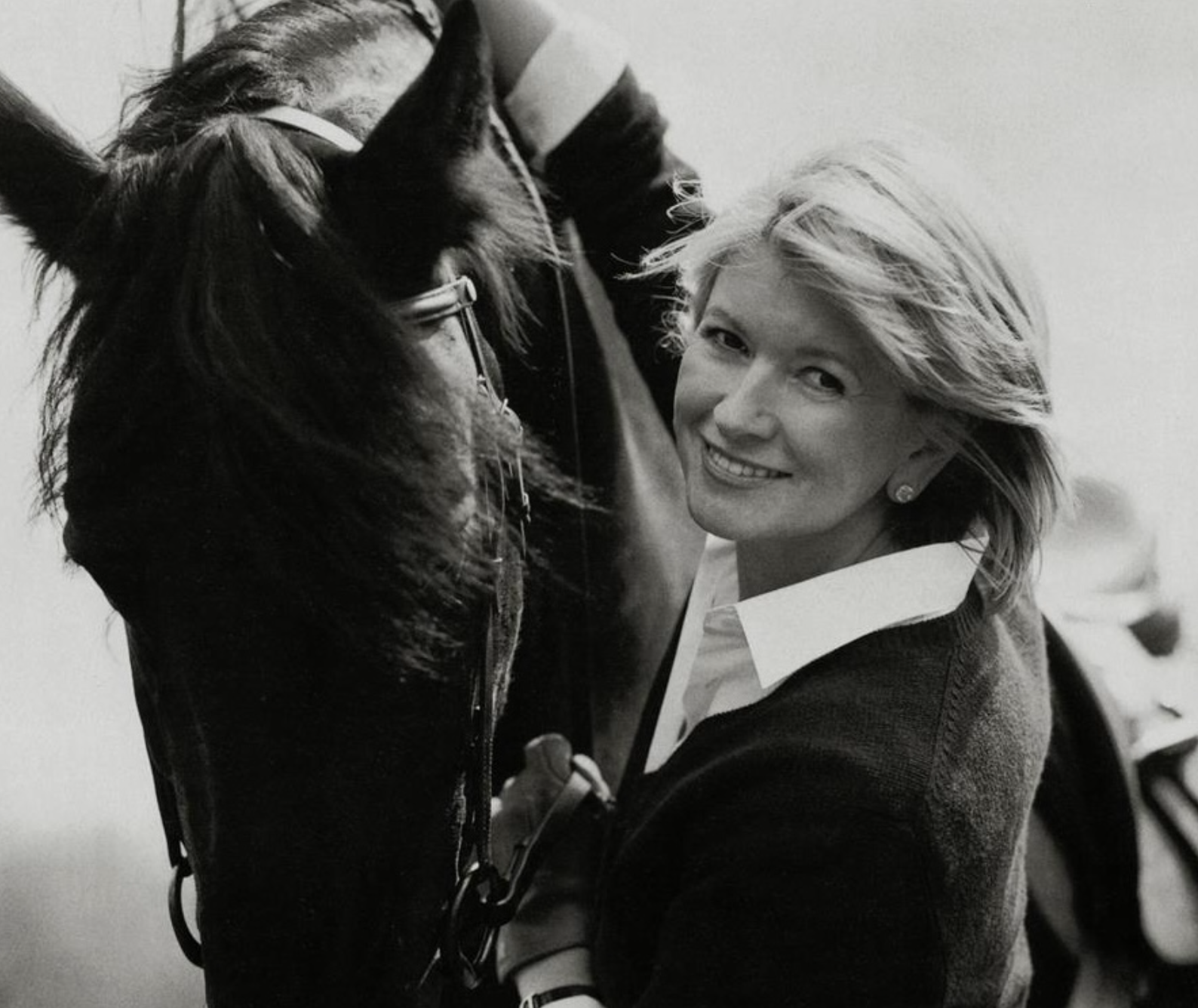 A woman with short blonde hair smiling and looking at the camera, standing close to a person wearing a jacket with tiger print, who is facing away from the camera.