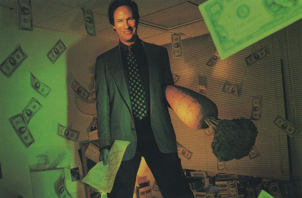 A man in a suit with a tie, standing in front of a wall with a carrot and a broccoli both enlarged, surrounded by falling dollar bills.